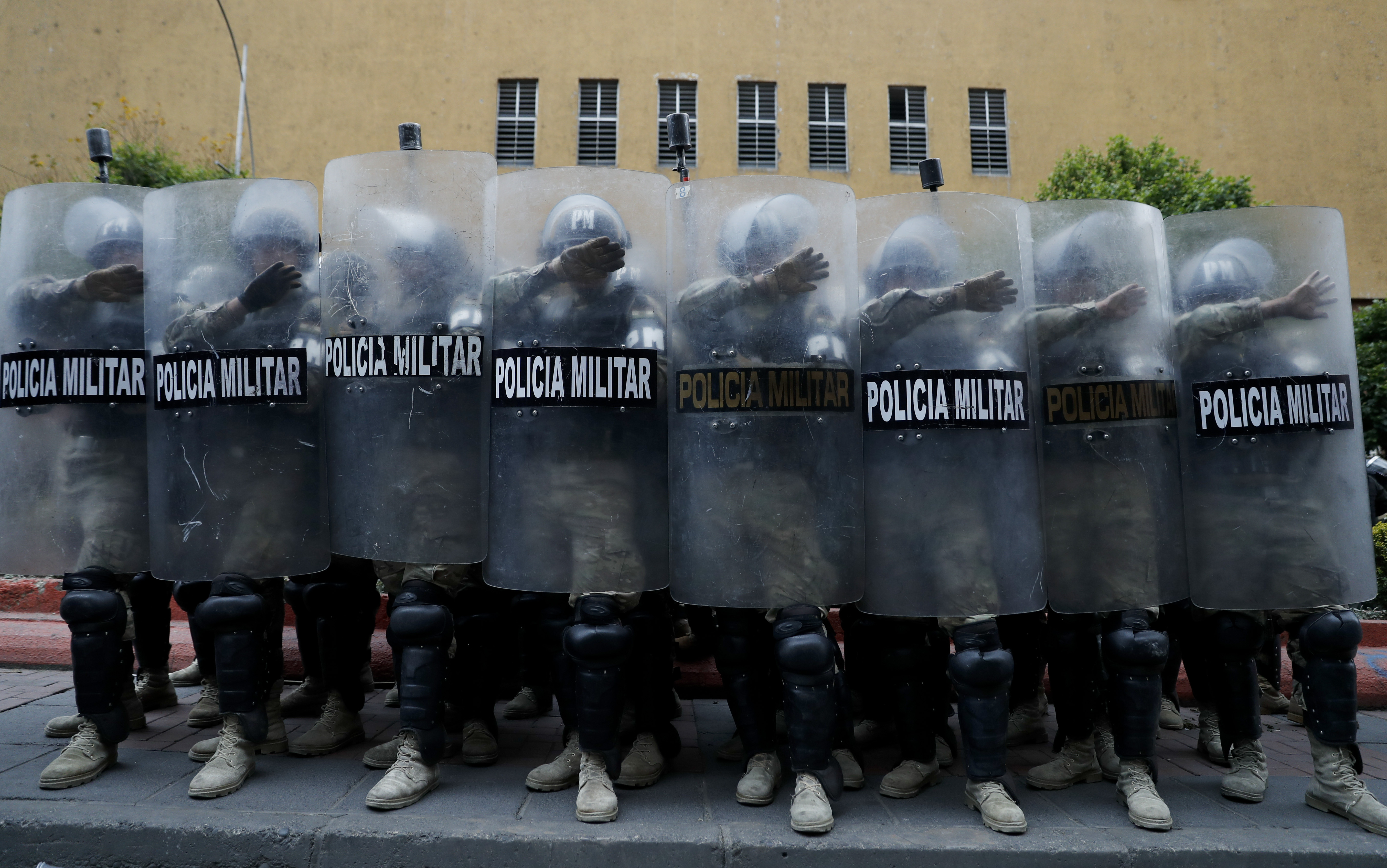 Police take cover behind their shields during a march of supporters of former President Evo Morales in La Paz, Bolivia on Thursday.