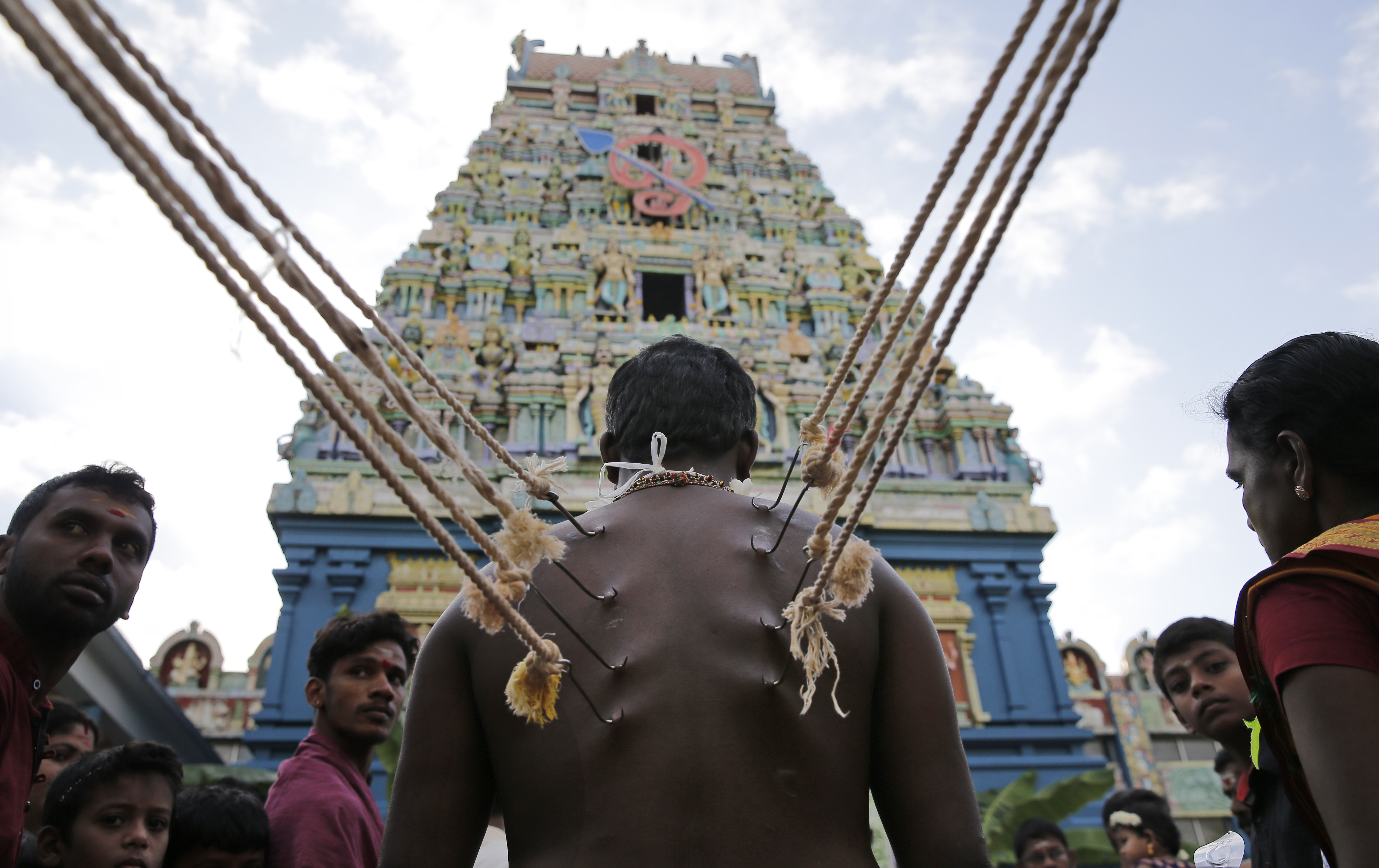 A Sri Lankan Hindu devotee stands with his body pierced with metal hooks as part of performing a ritual at a temple in Colombo.