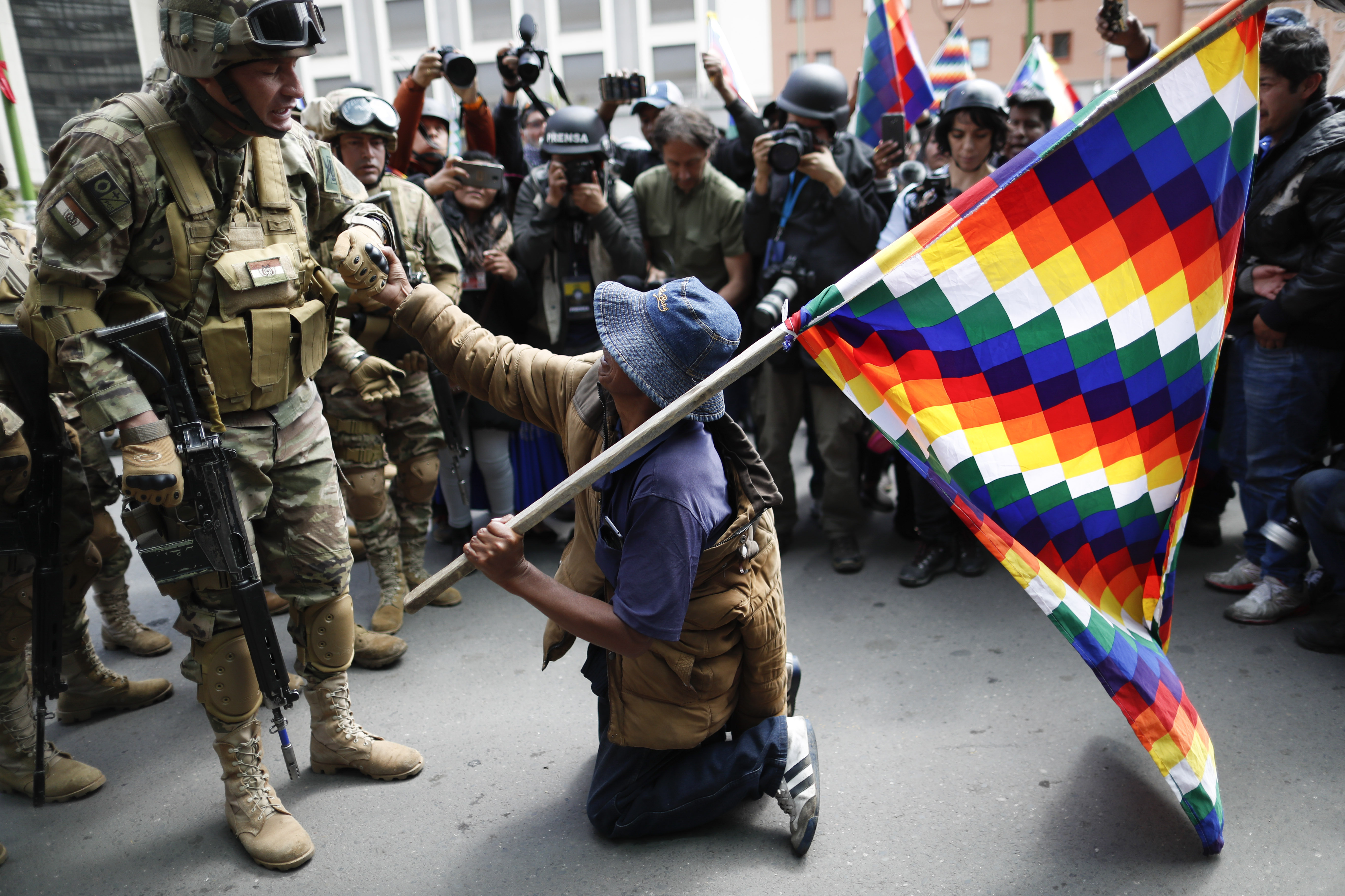 A backer of former President Evo Morales kneels in front of soldiers guarding a street in downtown La Paz, Bolivia, on Friday.