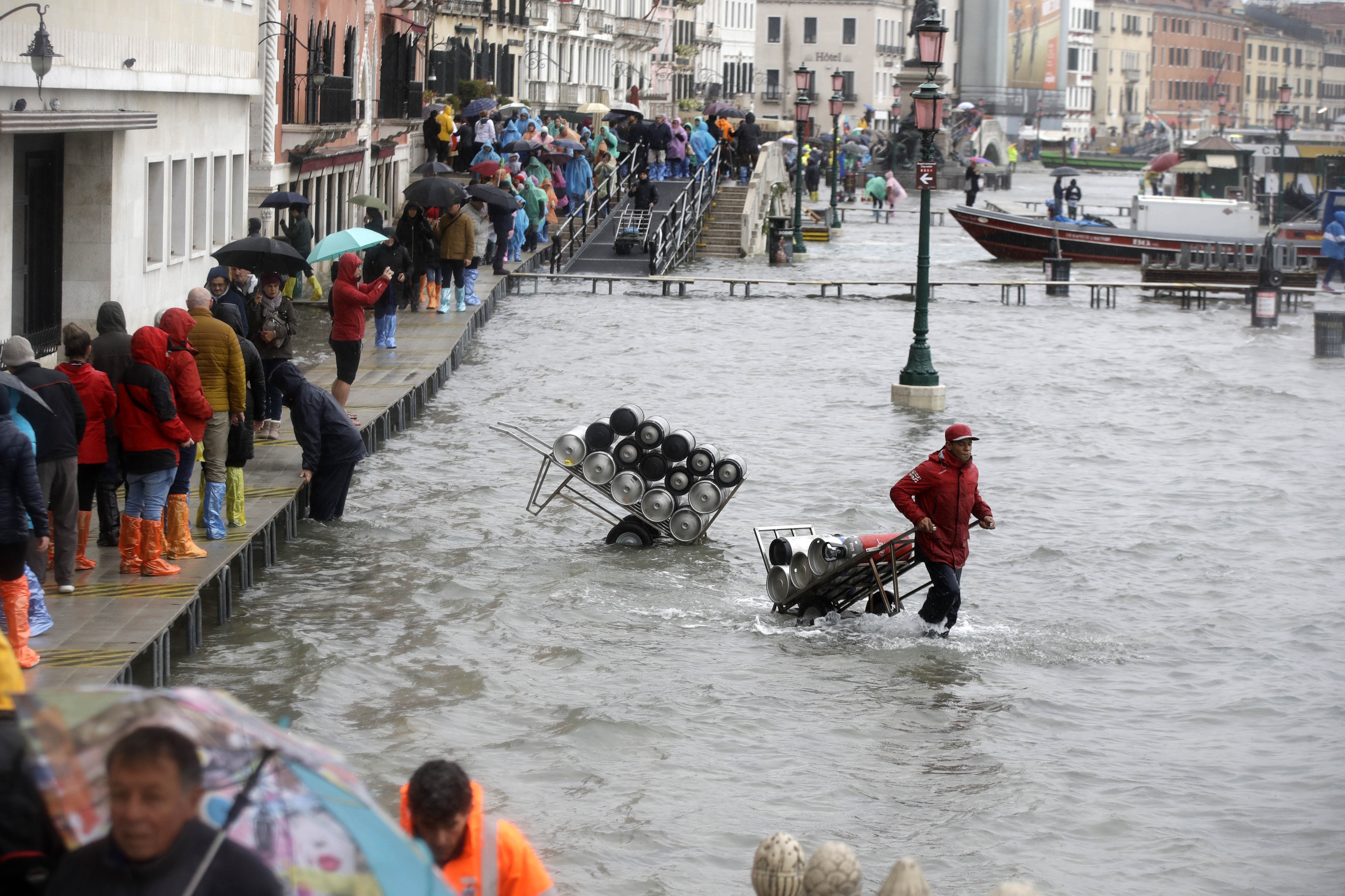 People walk on catwalk set up on the occasion of a high tide, in a flooded Venice, Italy.