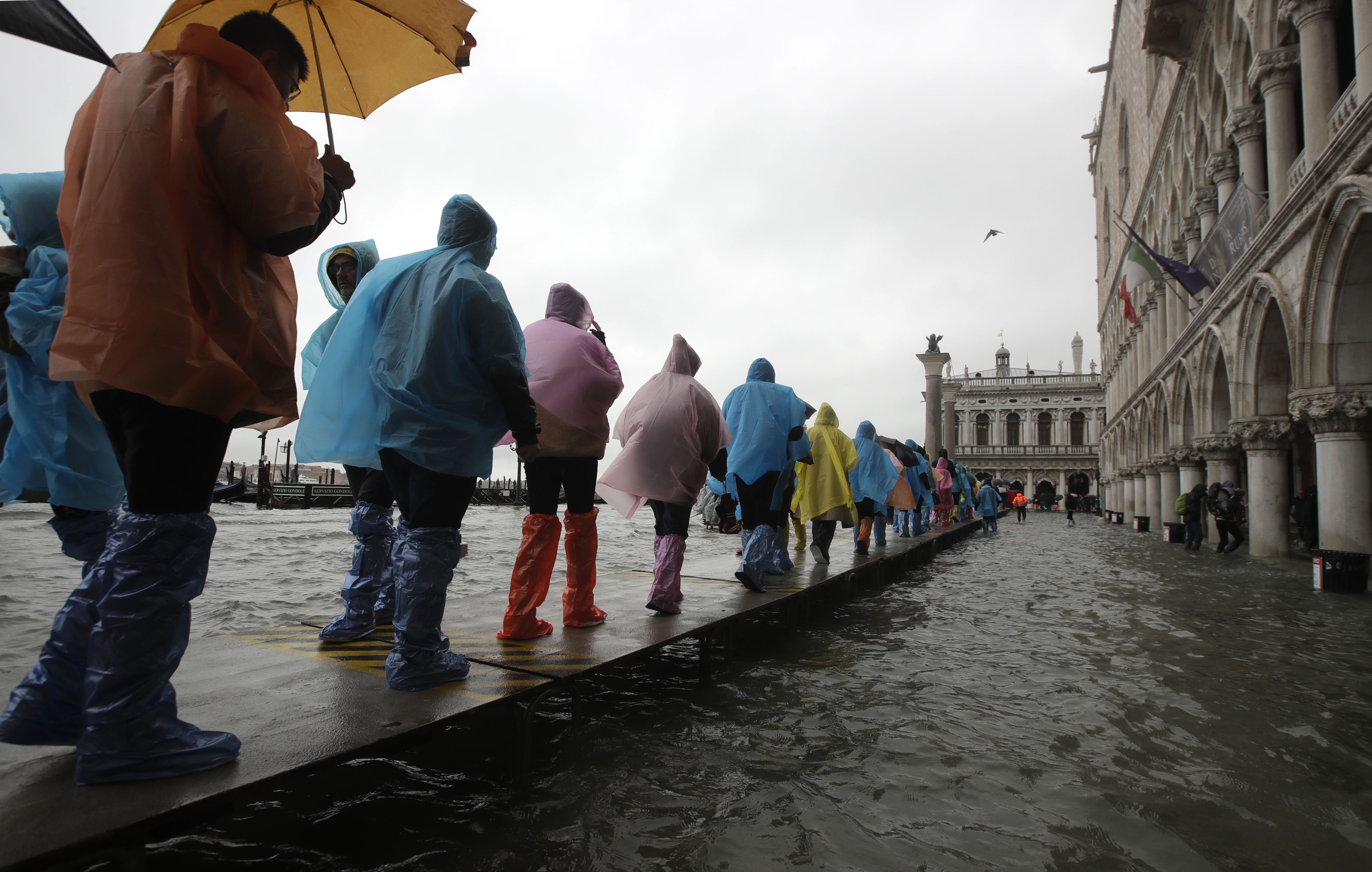 People walk on catwalk set up on the occasion of a high tide, in a flooded Venice, Italy.