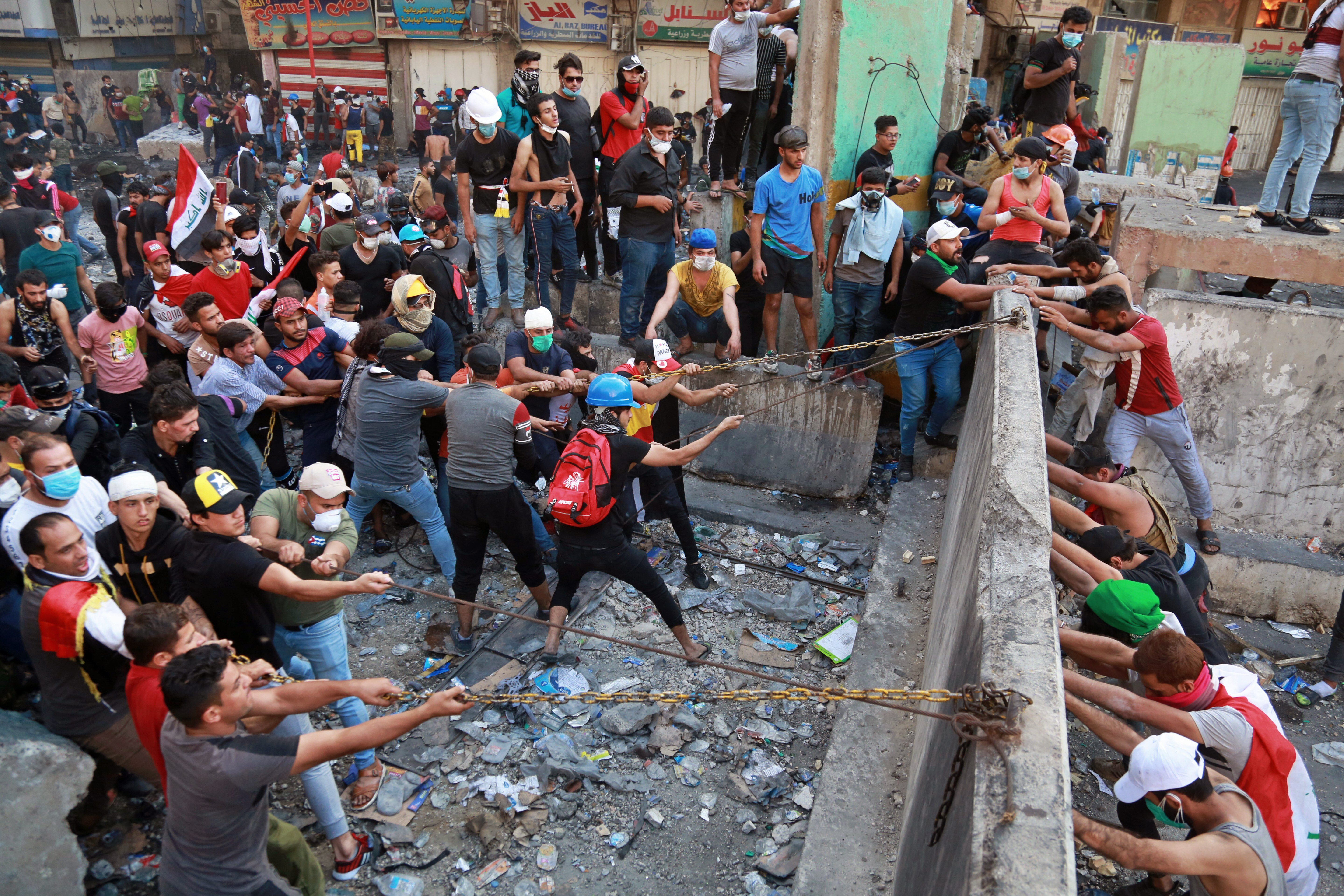 Protesters try to pull down concrete walls placed by Iraqi security forces during clashes between Iraqi security forces and anti-government demonstrators, at Khilani Square in Baghdad, Iraq, on Friday.