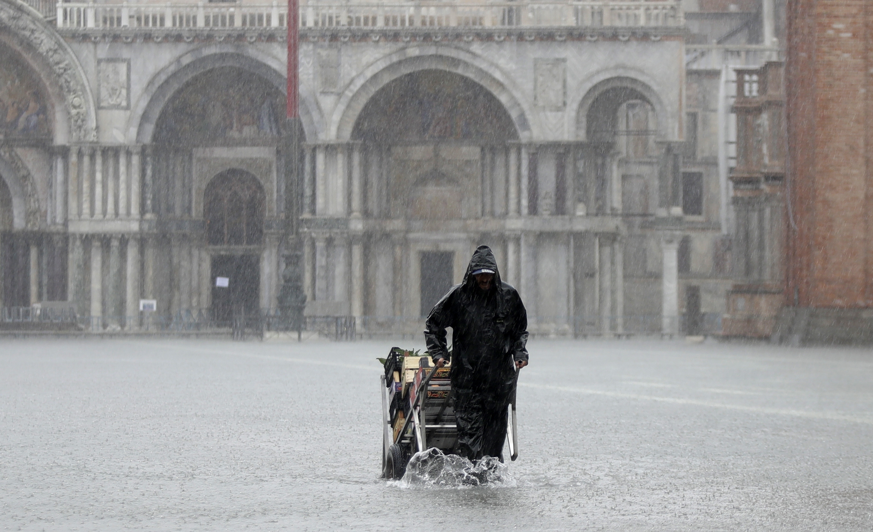 A greengrocer carries his cart as the water begins to flood St. Mark's Square on the occasion of a high tide in Venice.