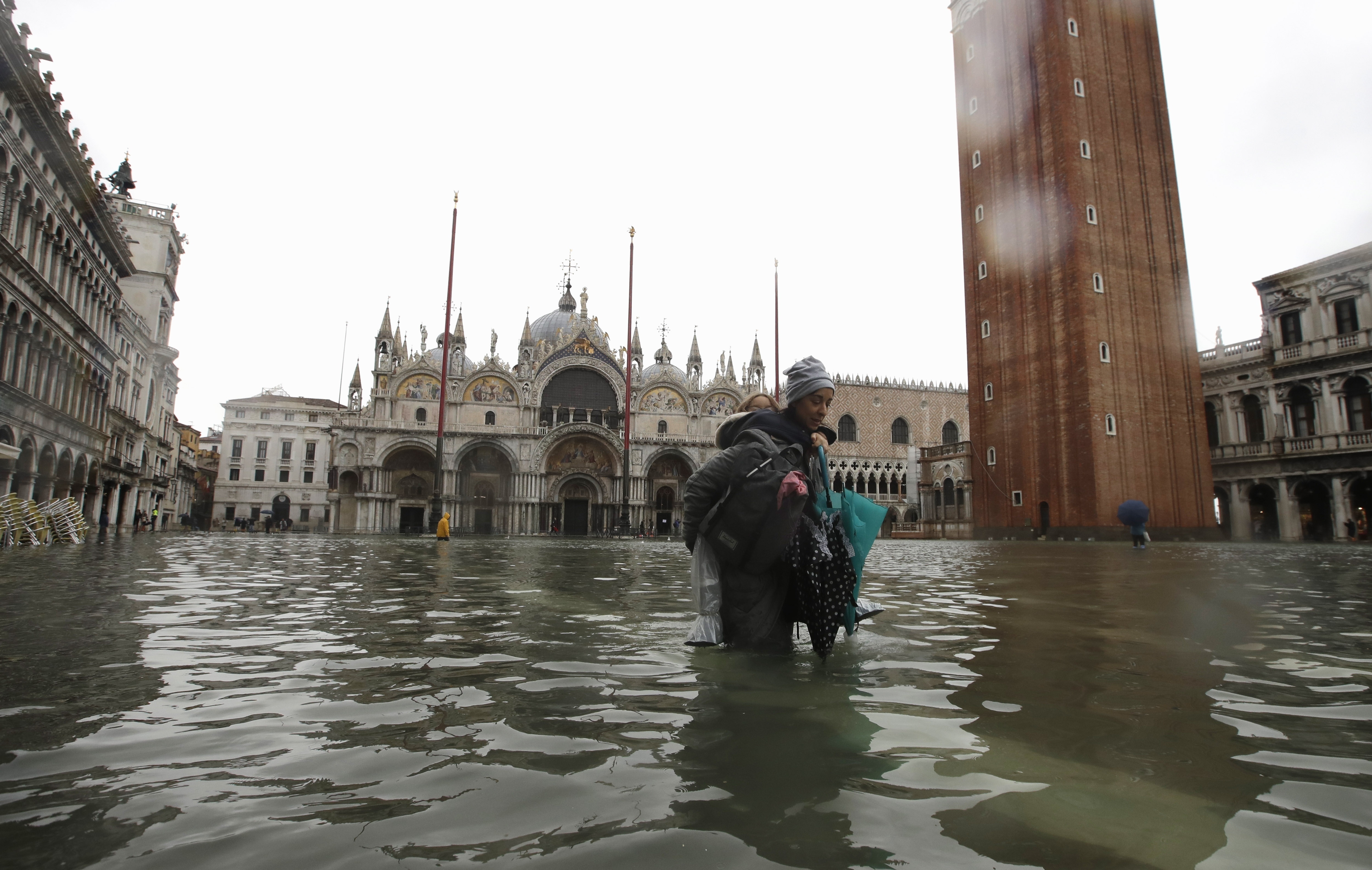 A woman carries her daughter in a flooded St. Mark's Square in Venice.