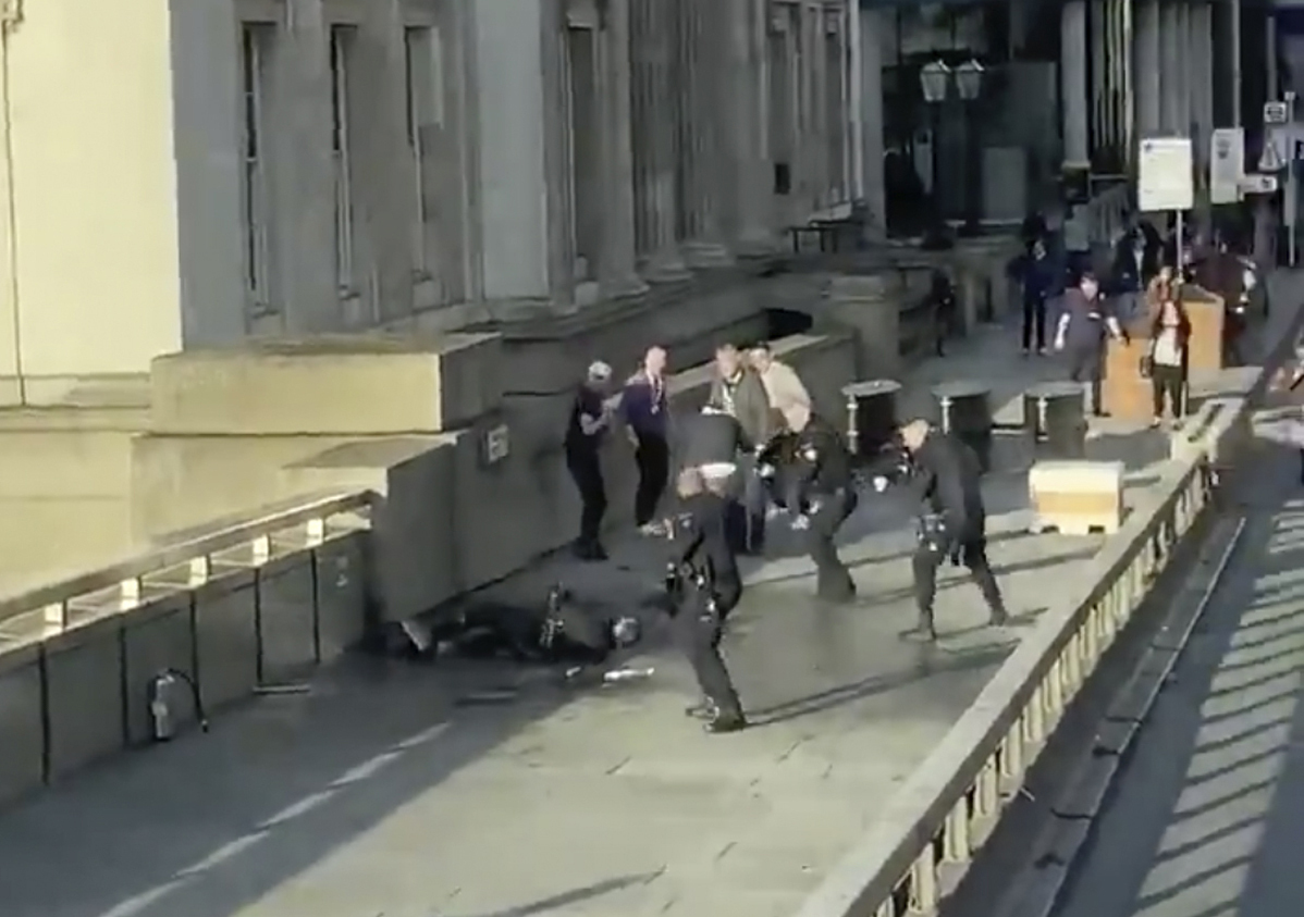 In this grab taken from video made available by @HLOBlog, a man is surrounded by police after an incident on London Bridge, in London, on Friday.