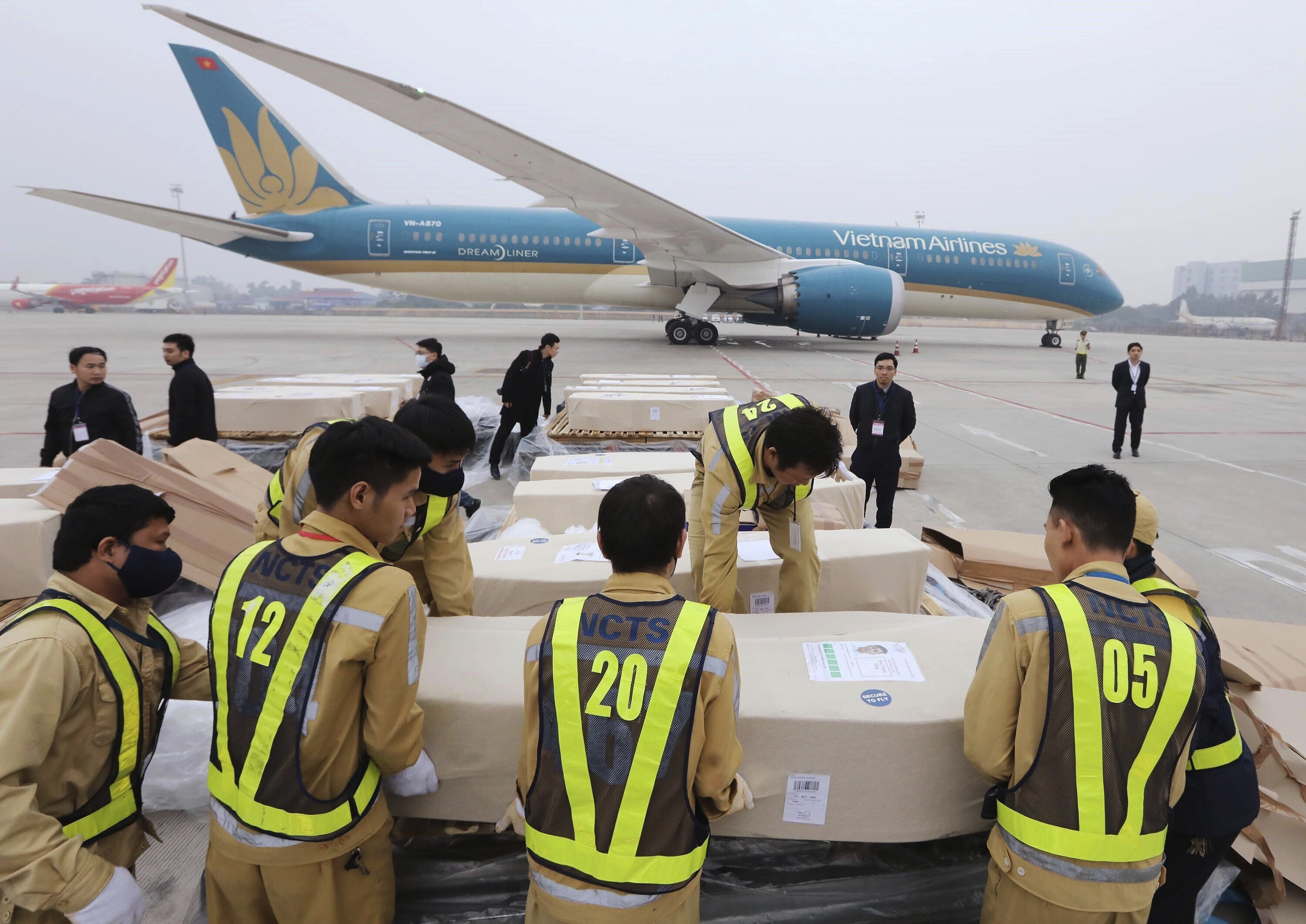 Airport personnel line up a row of coffins on the tarmac of the Noi Bai airport in Hanoi, Vietnam, on Saturday.