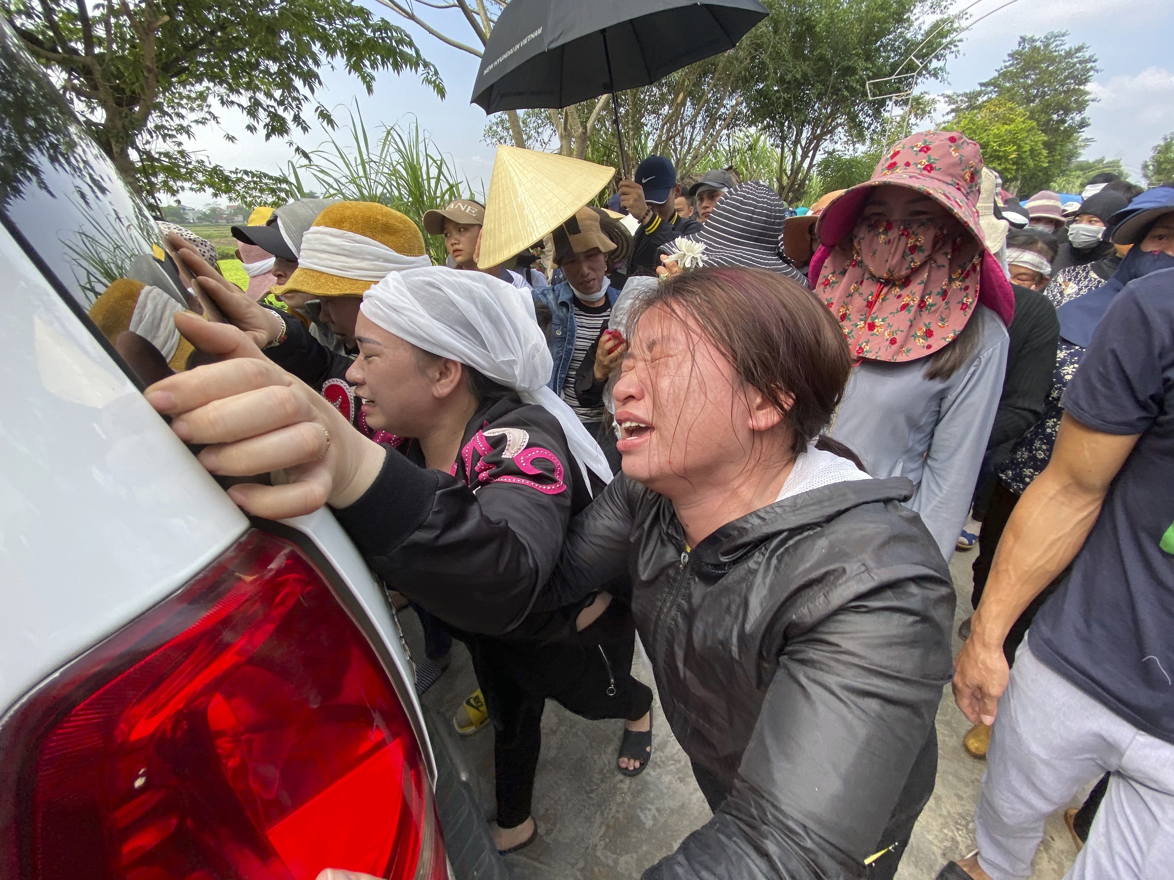 The sisters of Bui Thi Nhung weep as they walk behind the ambulance that carries Nhung's casket on Saturday in the village of Do Thanh, Vietnam.