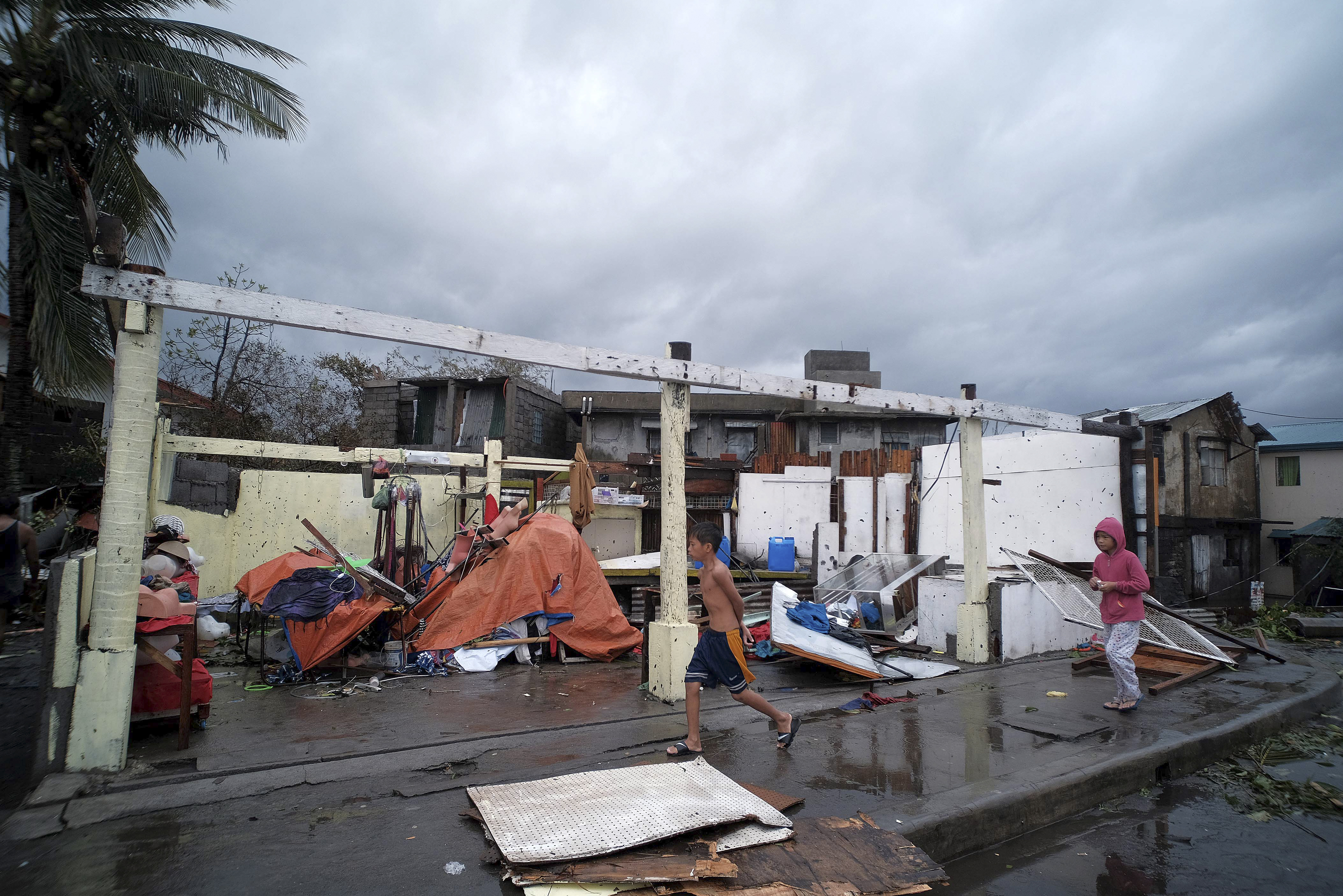 Children pass by damaged homes due to strong winds as Typhoon Kammuri slammed southeast of Manila, Philippines on Tuesday.