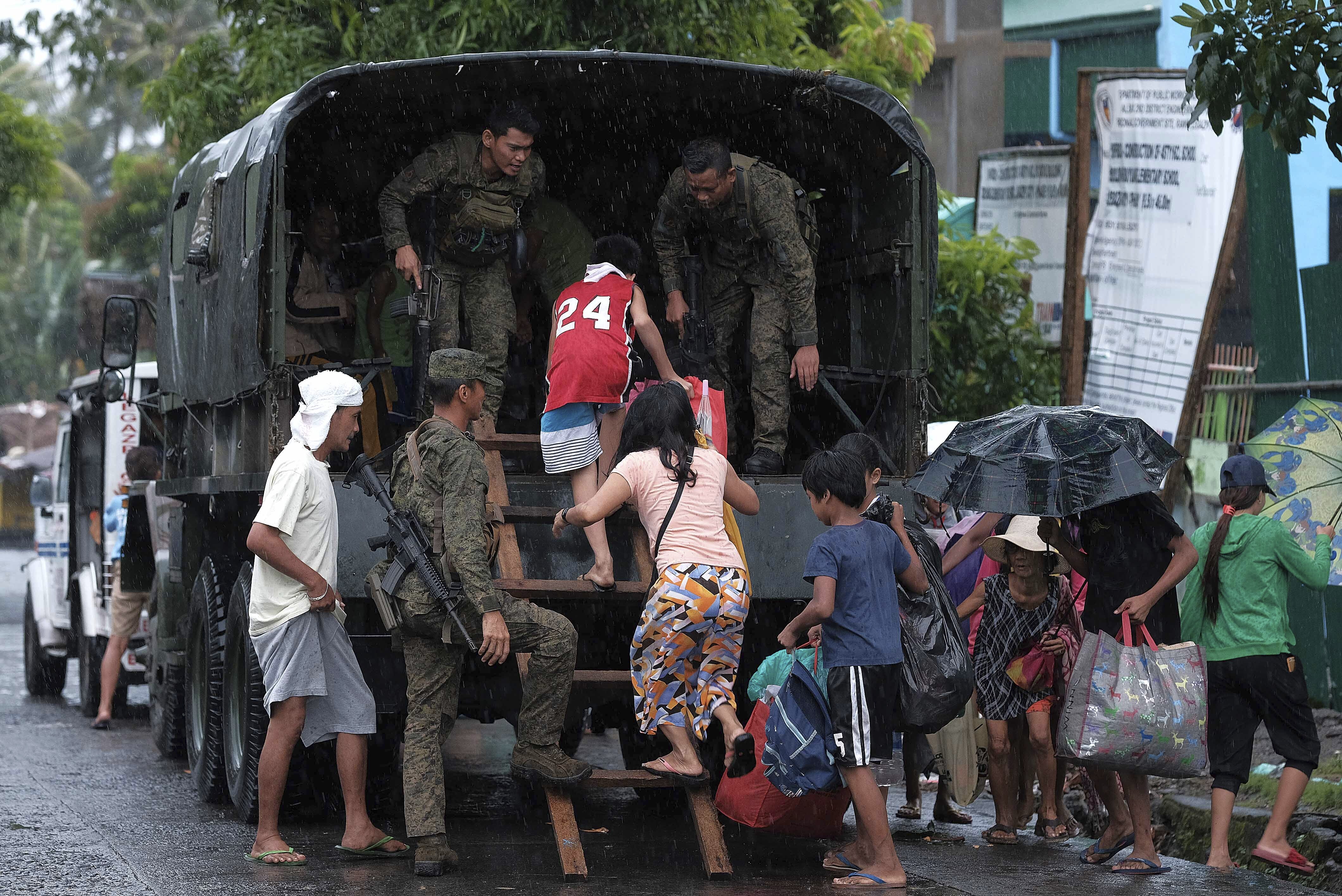 Residents ride a military truck as they evacuate to safer grounds in preparation for the coming of Typhoon Kammuri southeast of Manila, Philippines, on Monday.