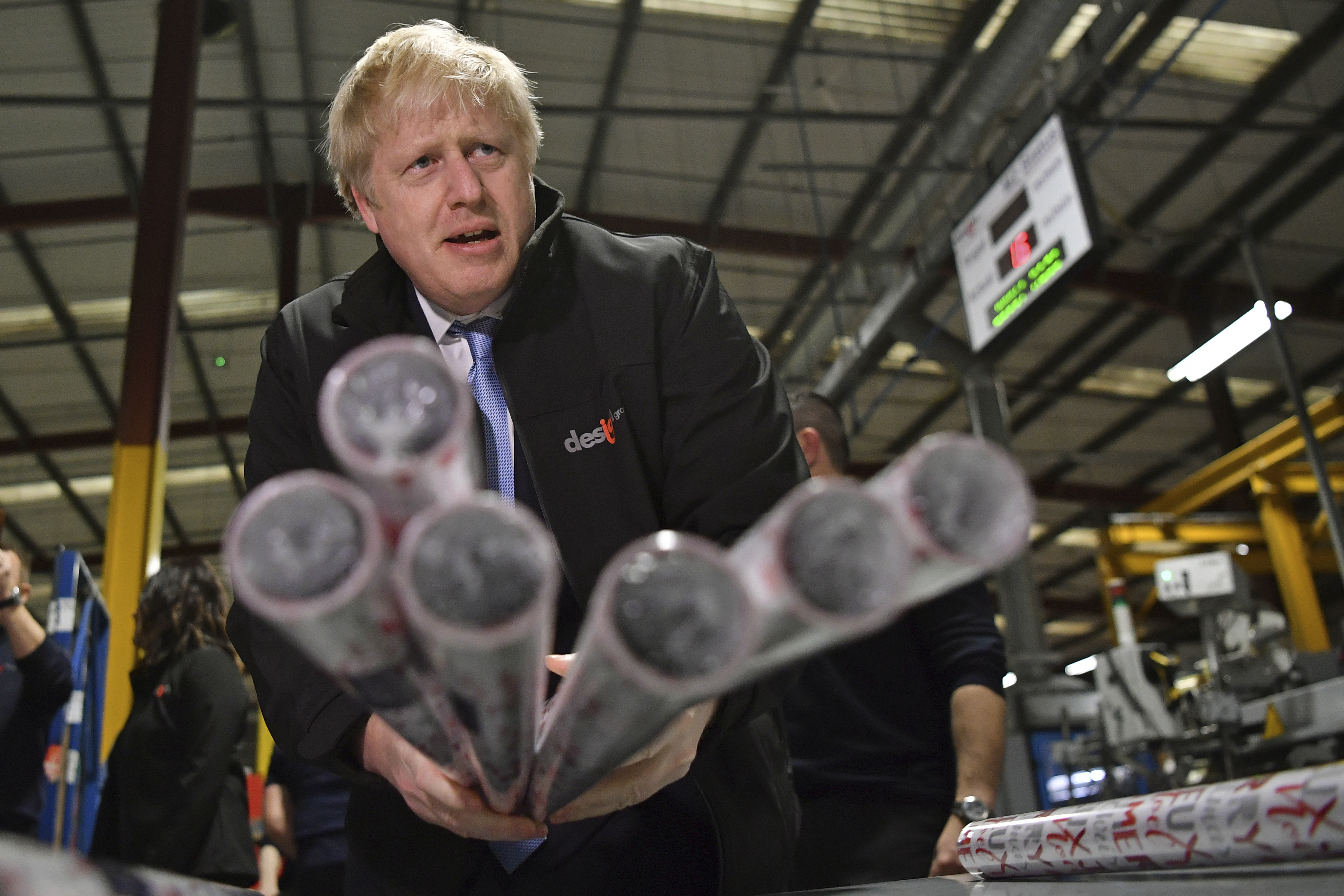 Britain's Prime Minister Boris Johnson, centre, gestures with Christmas wrapping paper, during a visit to IG Design Group