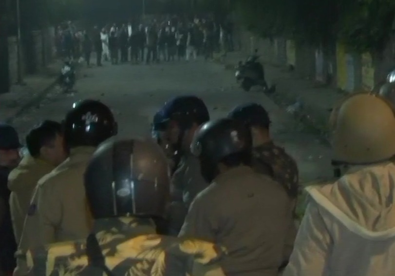 Police and protesters outside the campus of Jamia Millia Islamia University; tear gas shells fired at protesters by the police.