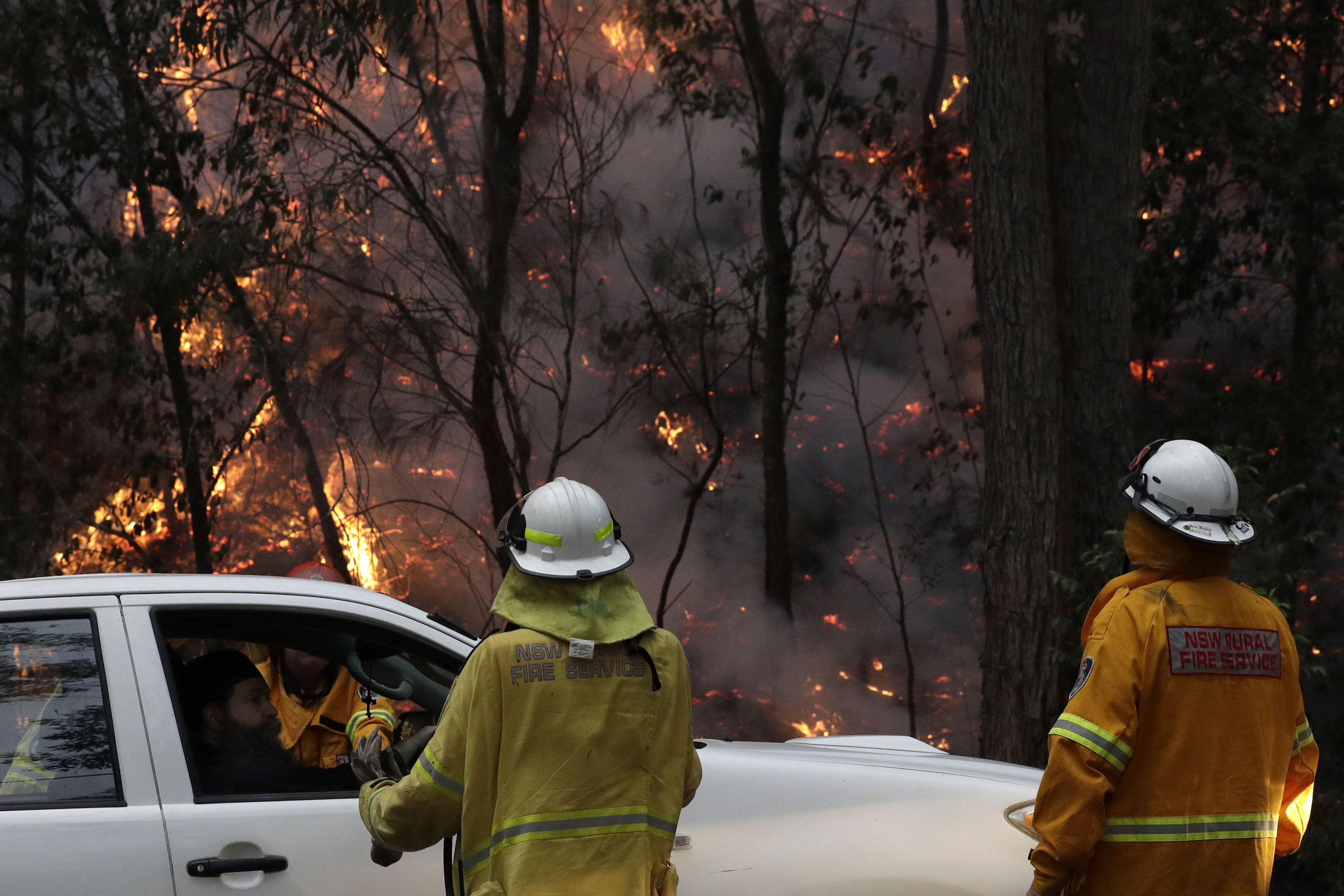 Firefighters talk with local residents as a fire burns near Mangrove Mountain, north of Sydney, on Tuesday.