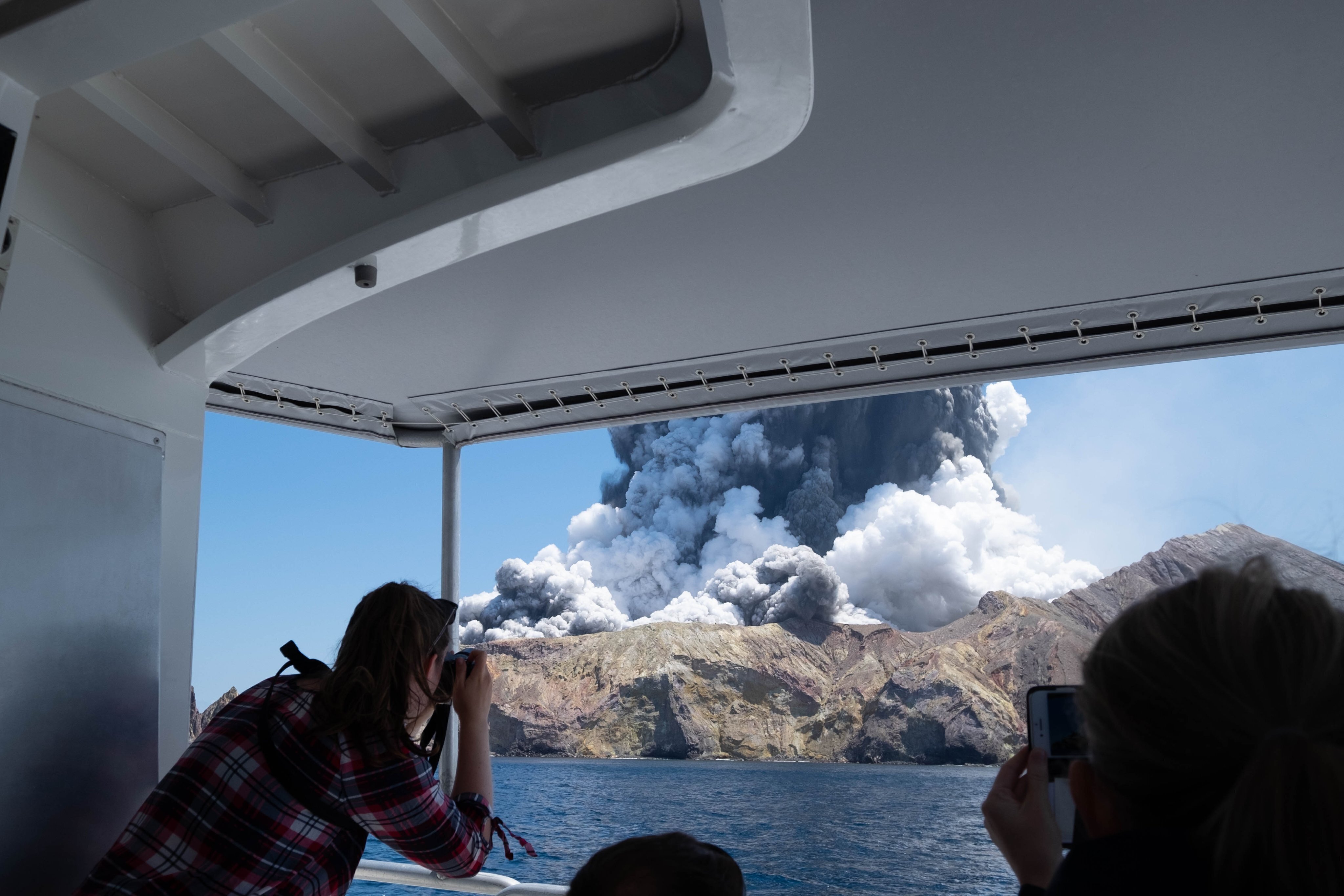 In this Dec. 9, 2019, file photo provided by Michael Schade, tourists on a boat look at the eruption of the volcano on White Island, New Zealand.