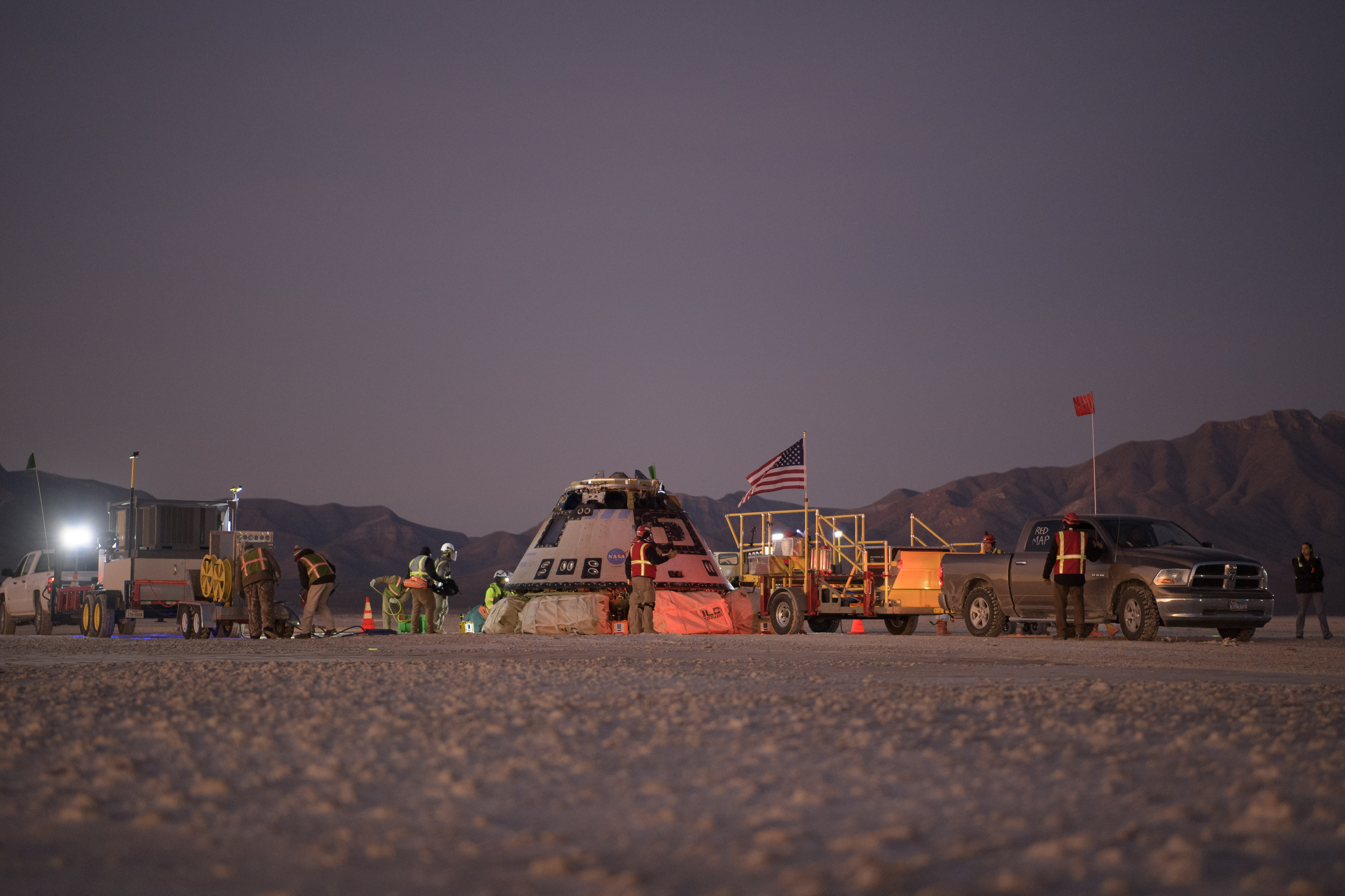 Boeing, NASA, and U.S. Army personnel work around the Boeing Starliner spacecraft shortly after it landed in White Sands, New Mexico, on Sunday.