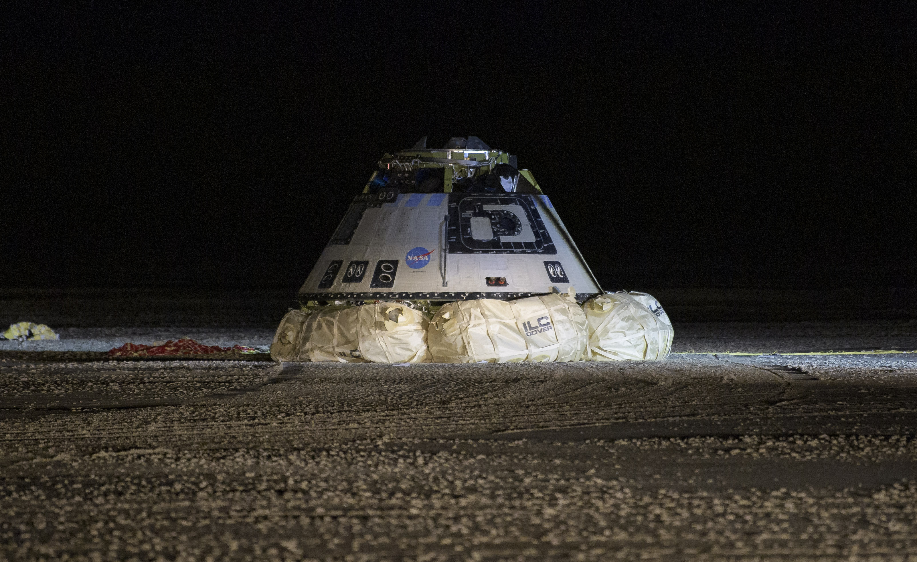 Boeing, NASA, and U.S. Army personnel work around the Boeing Starliner spacecraft shortly after it landed in White Sands, New Mexico, on Sunday.