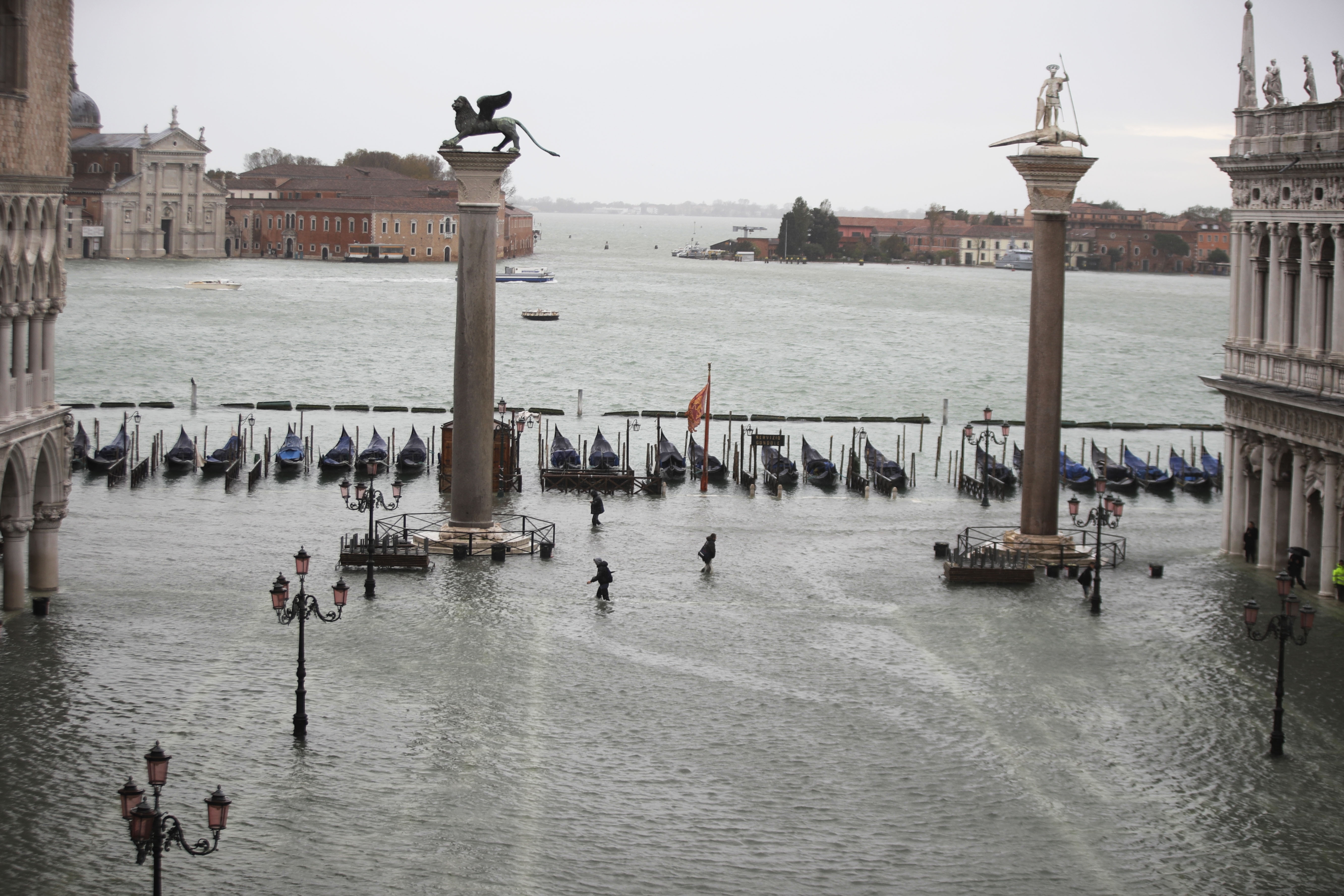 People wade their way through water in a flooded St. Mark's Square in Venice.