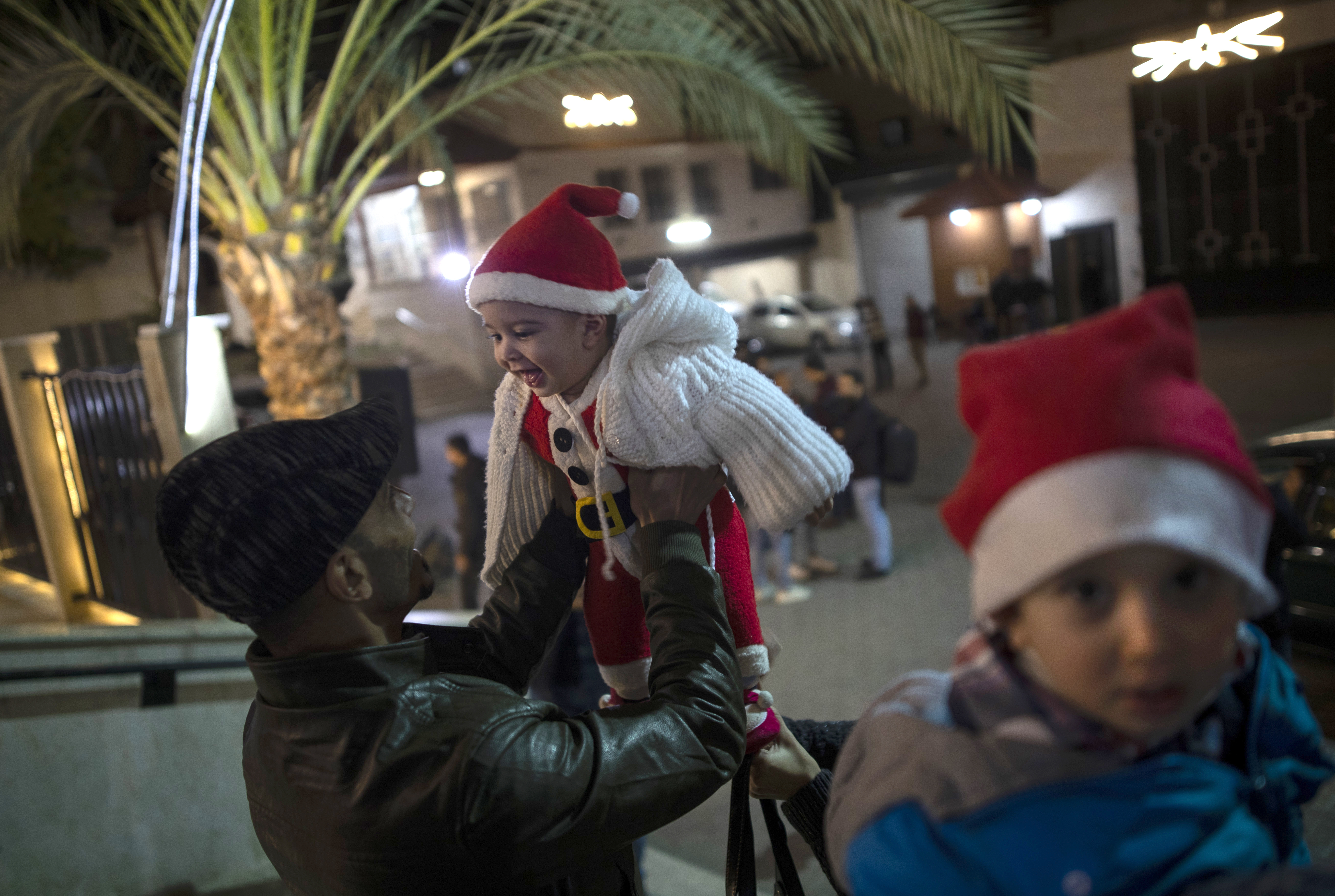 A Palestinian Christian man plays with his baby as they wait for the Christmas Mass outside the Holy Family Catholic Church in Gaza City.