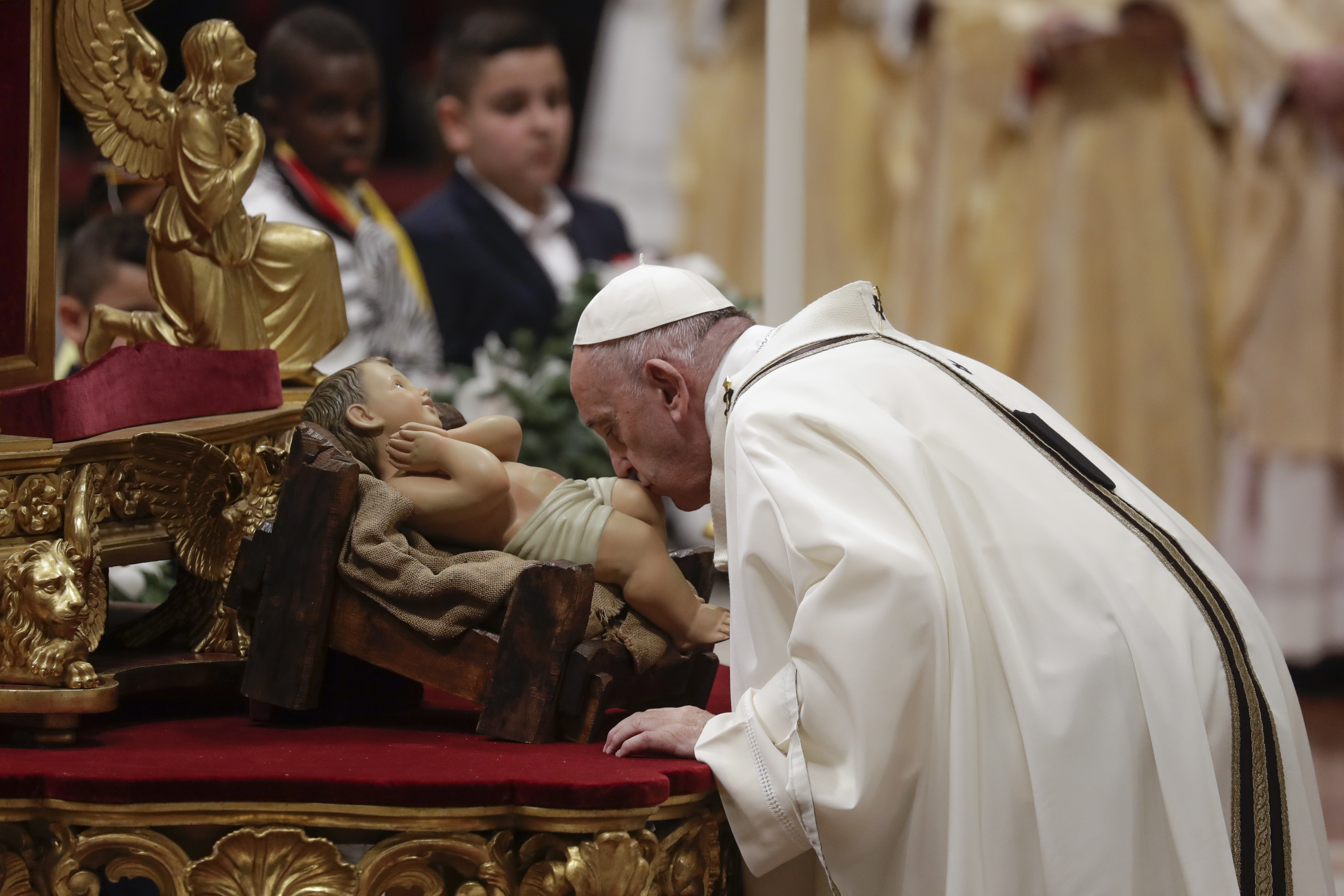 Pope Francis kisses a statue of Baby Jesus as he celebrates Christmas Eve Mass in St. Peter's Basilica at the Vatican