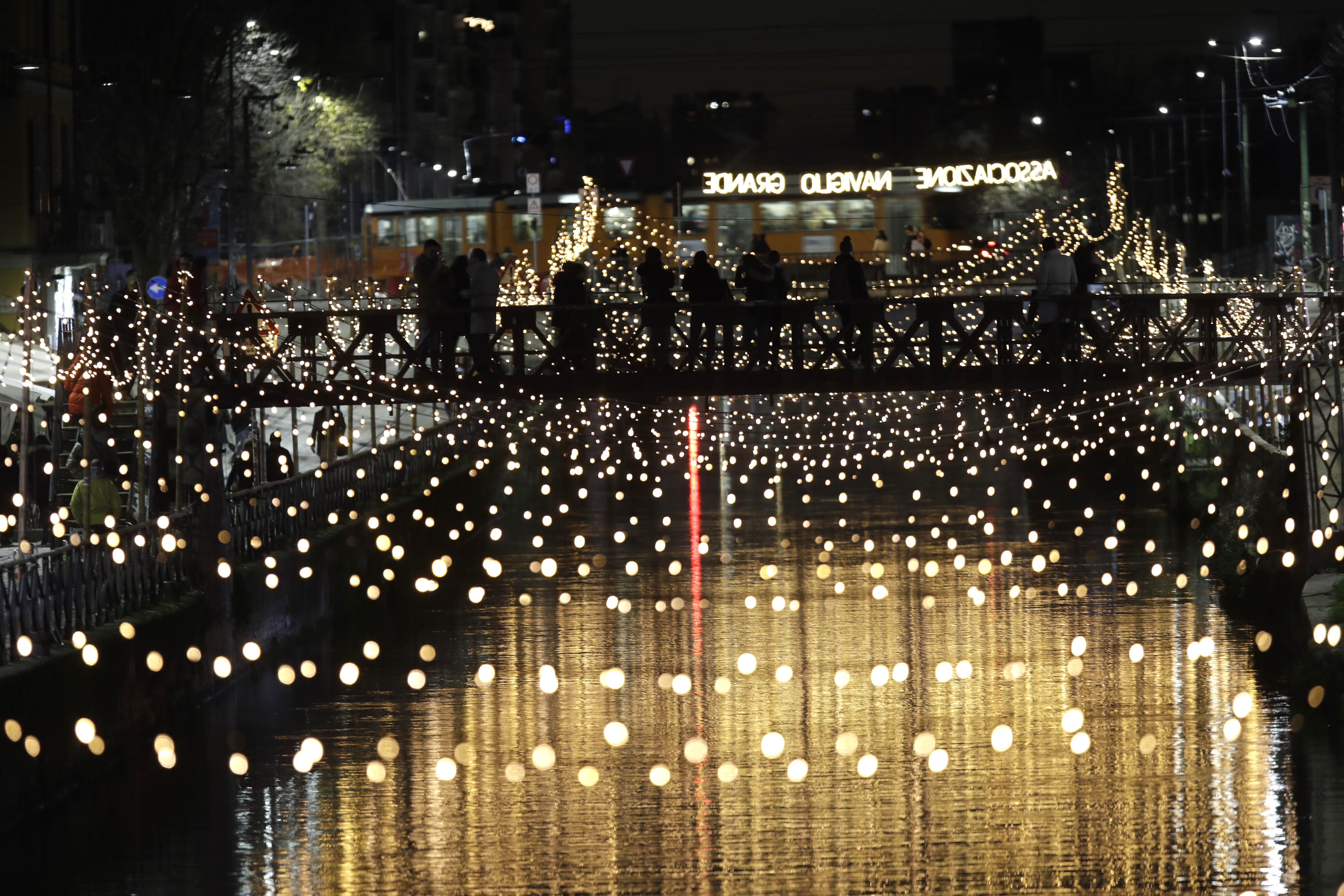 People walk on a bridge of the Naviglio Grande canal that was decorated with Christmas lights, in Milan, Italy.