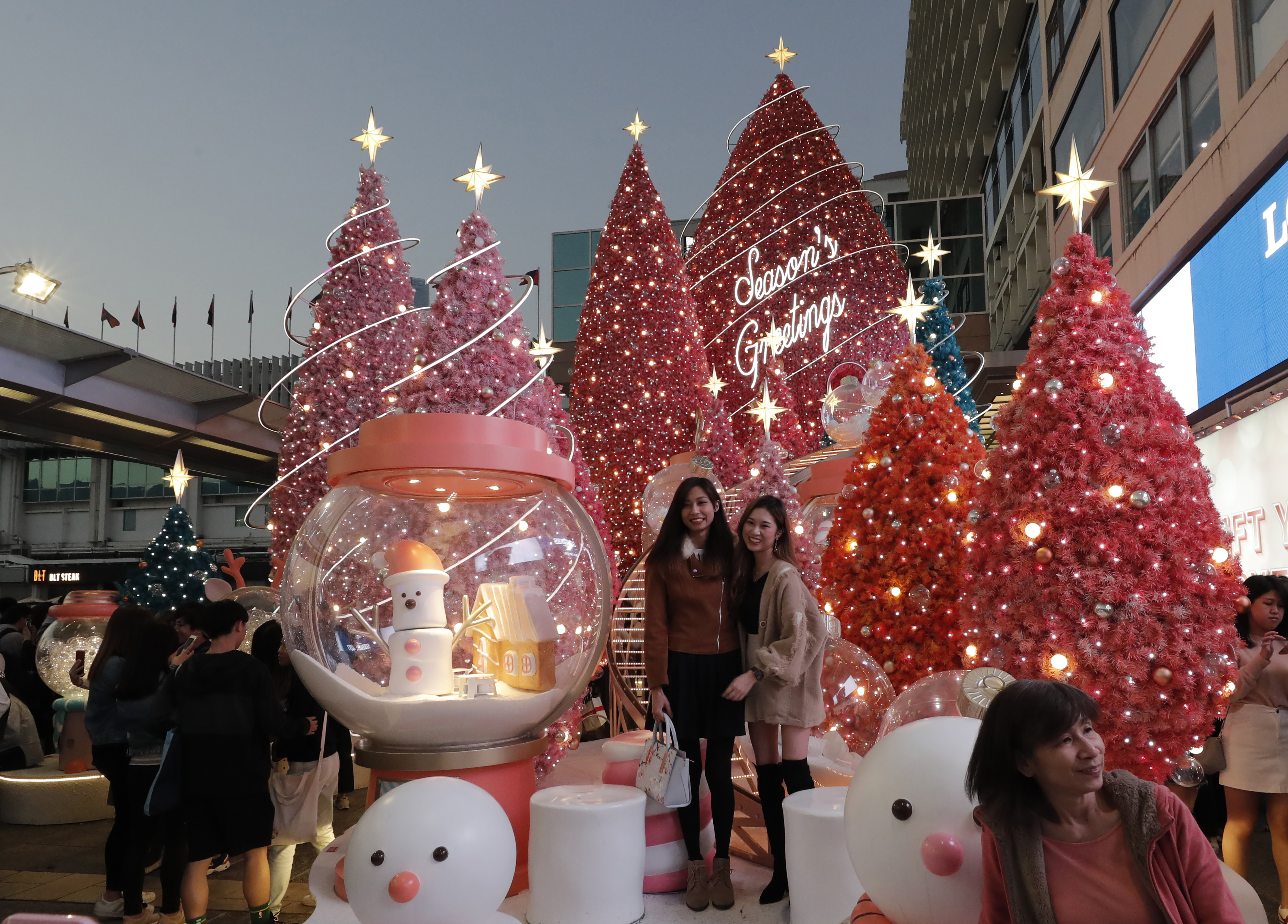 Visitors pose for photographs with Christmas trees at the Harbour City shopping mall in Hong Kong.