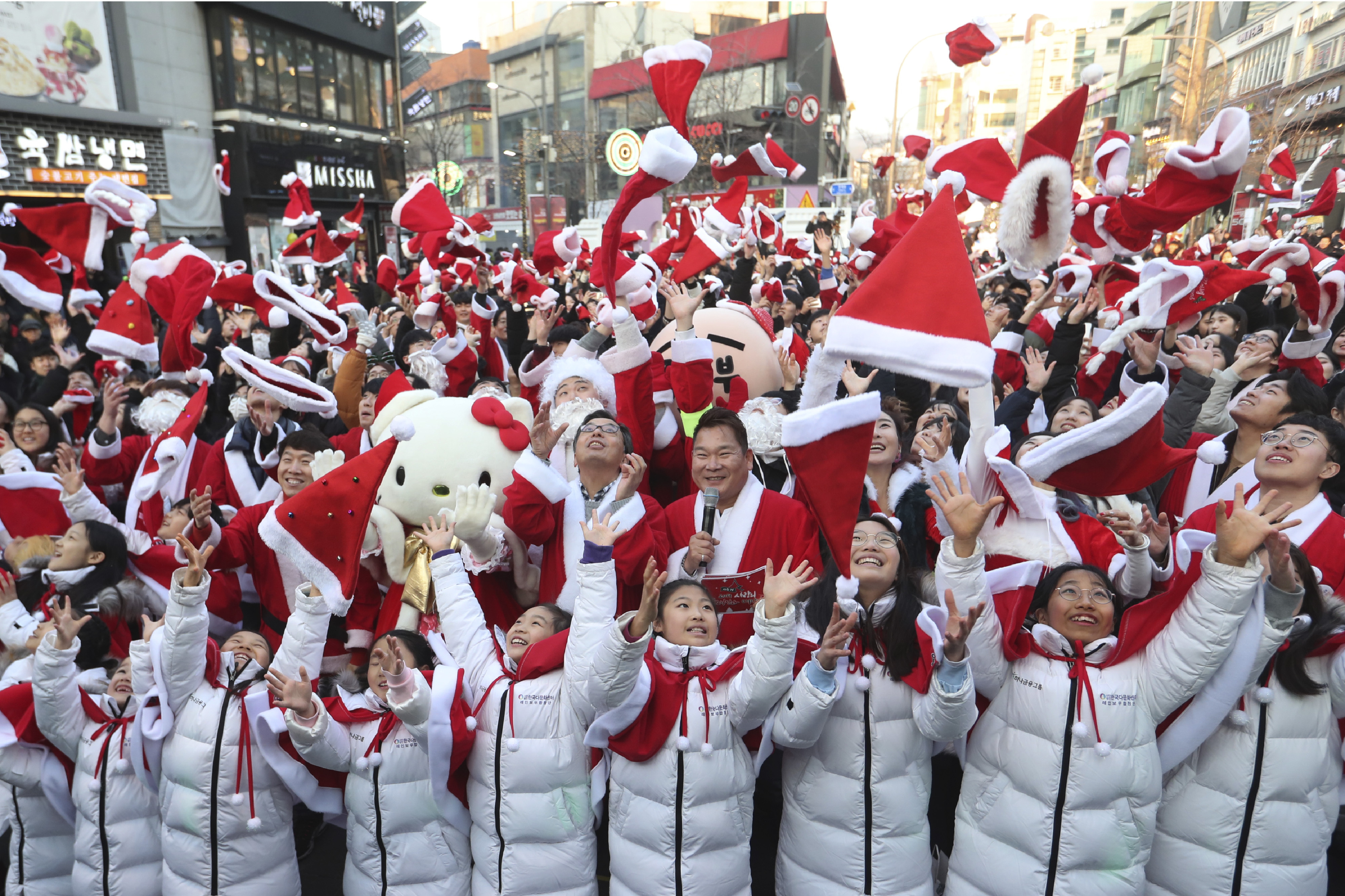 Volunteers and children clad in Santa Claus costumes throw their hats in the air during a Christmas charity event as they gather to deliver gifts for the poor in Seoul.