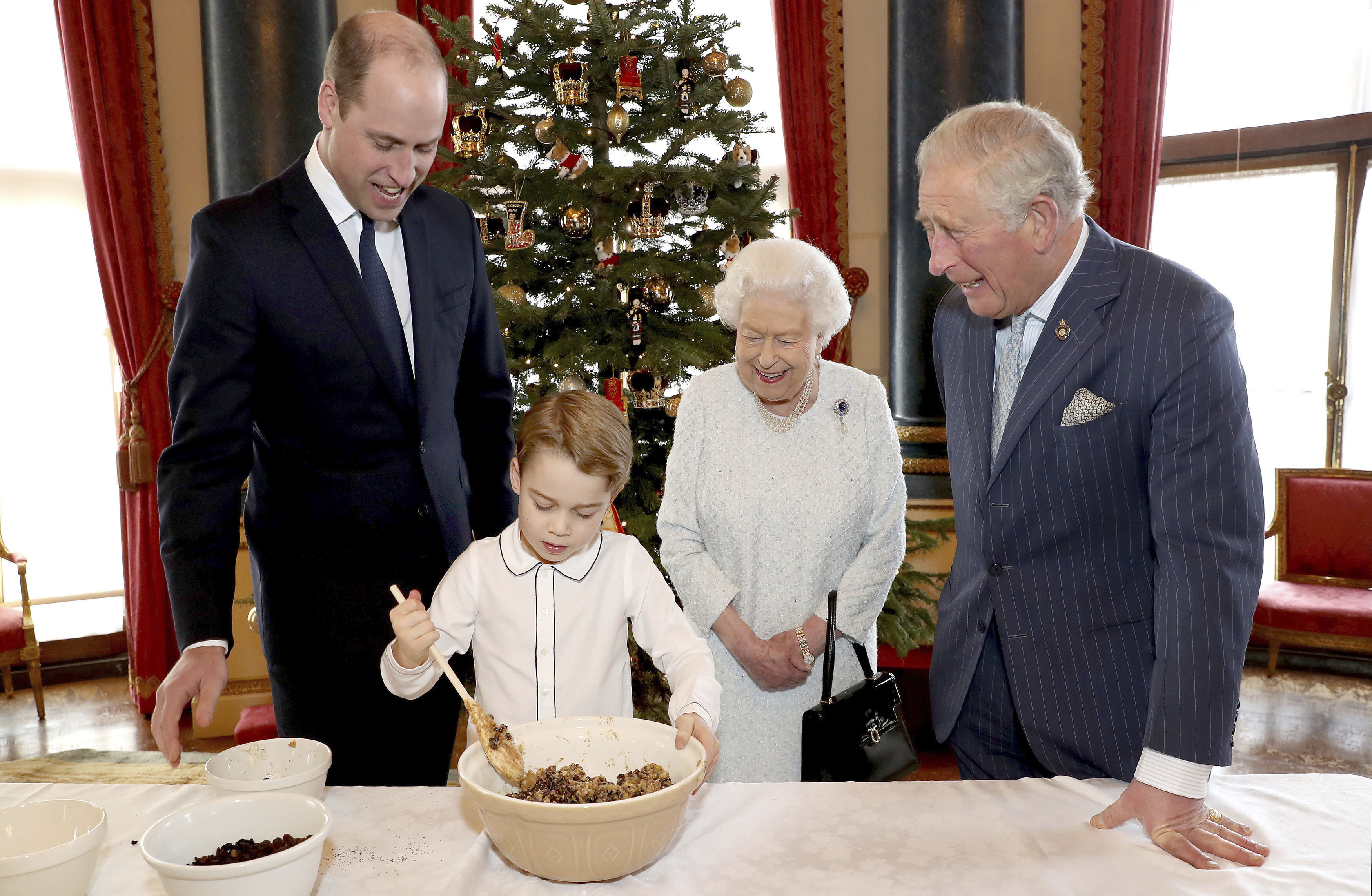 Britain's Queen Elizabeth, Prince Charles, Prince William and Prince George smile as they prepare special Christmas puddings in the Music Room at Buckingham Palace in London.