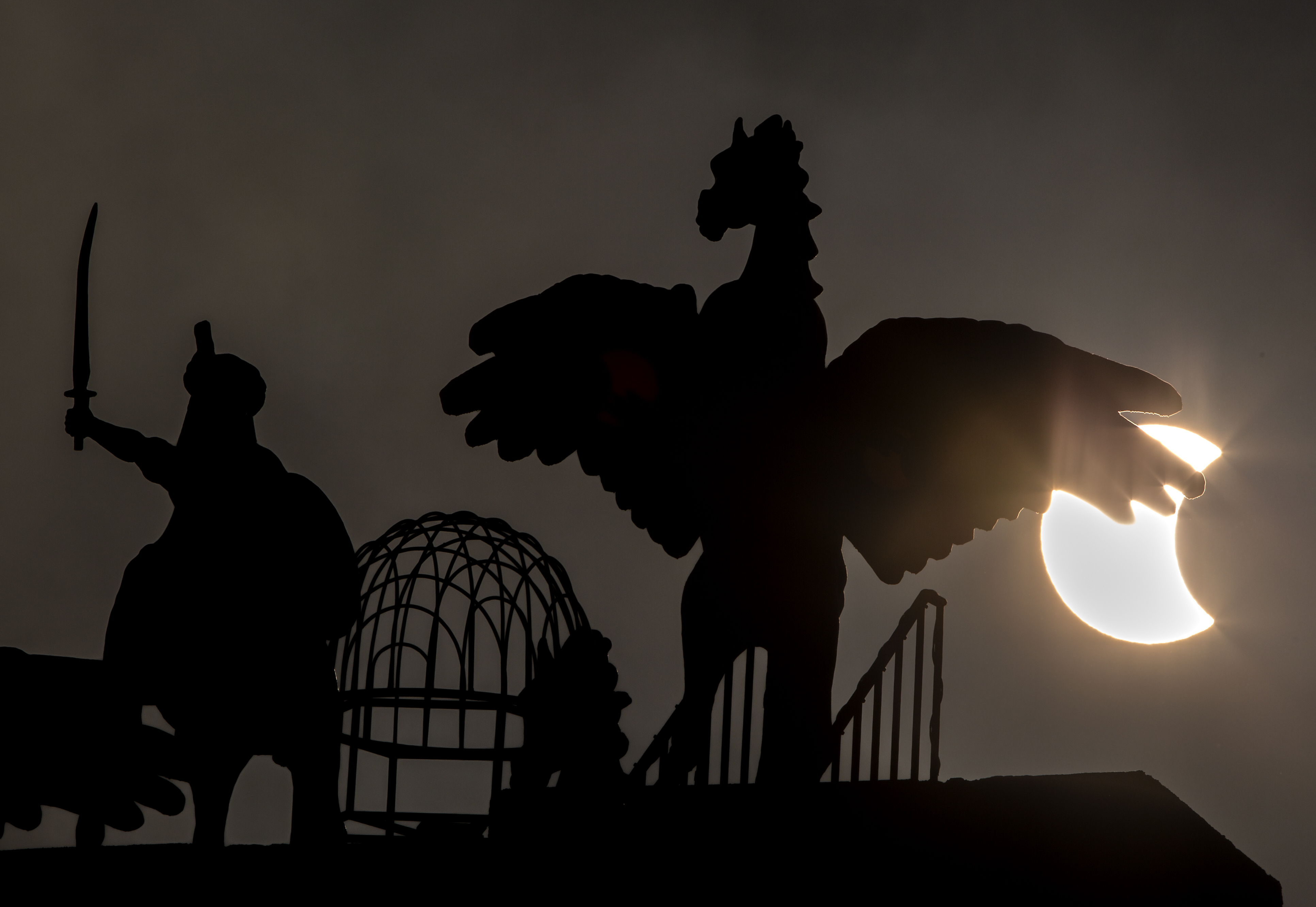 A partial solar eclipse moves behind statues in Islamabad, on Thursday.