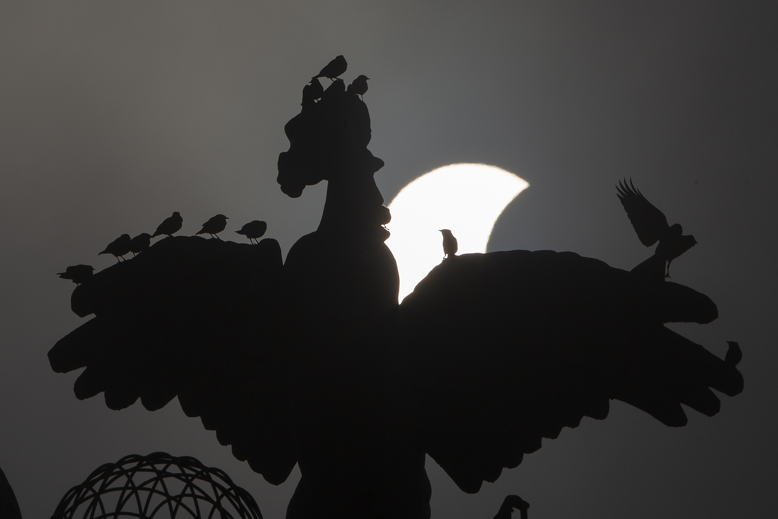 A partial solar eclipse moves behind a statue in Islamabad, on Thursday.