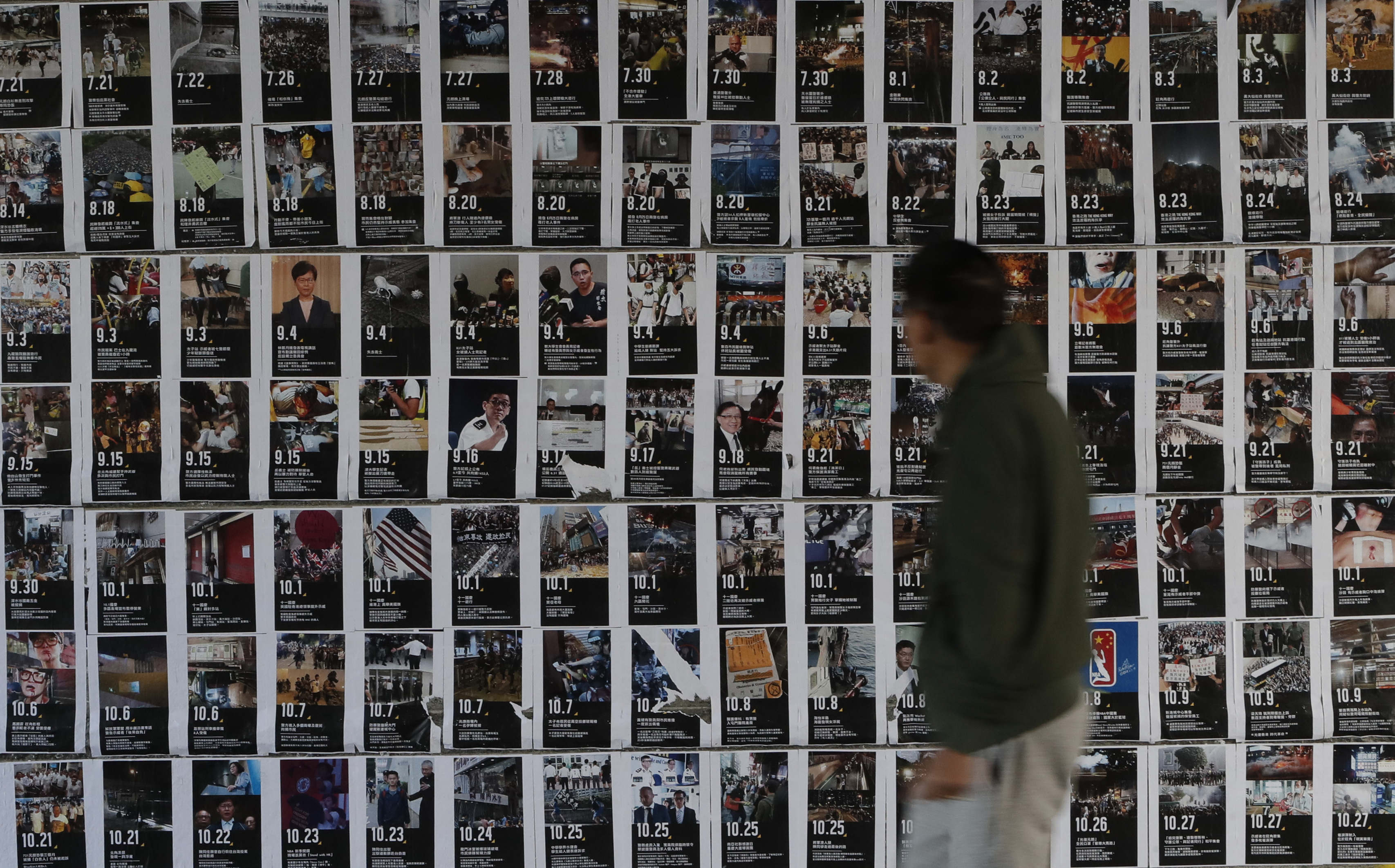 A man walks past a wall of posters featuring demonstration scenes in Hong Kong, on Friday.