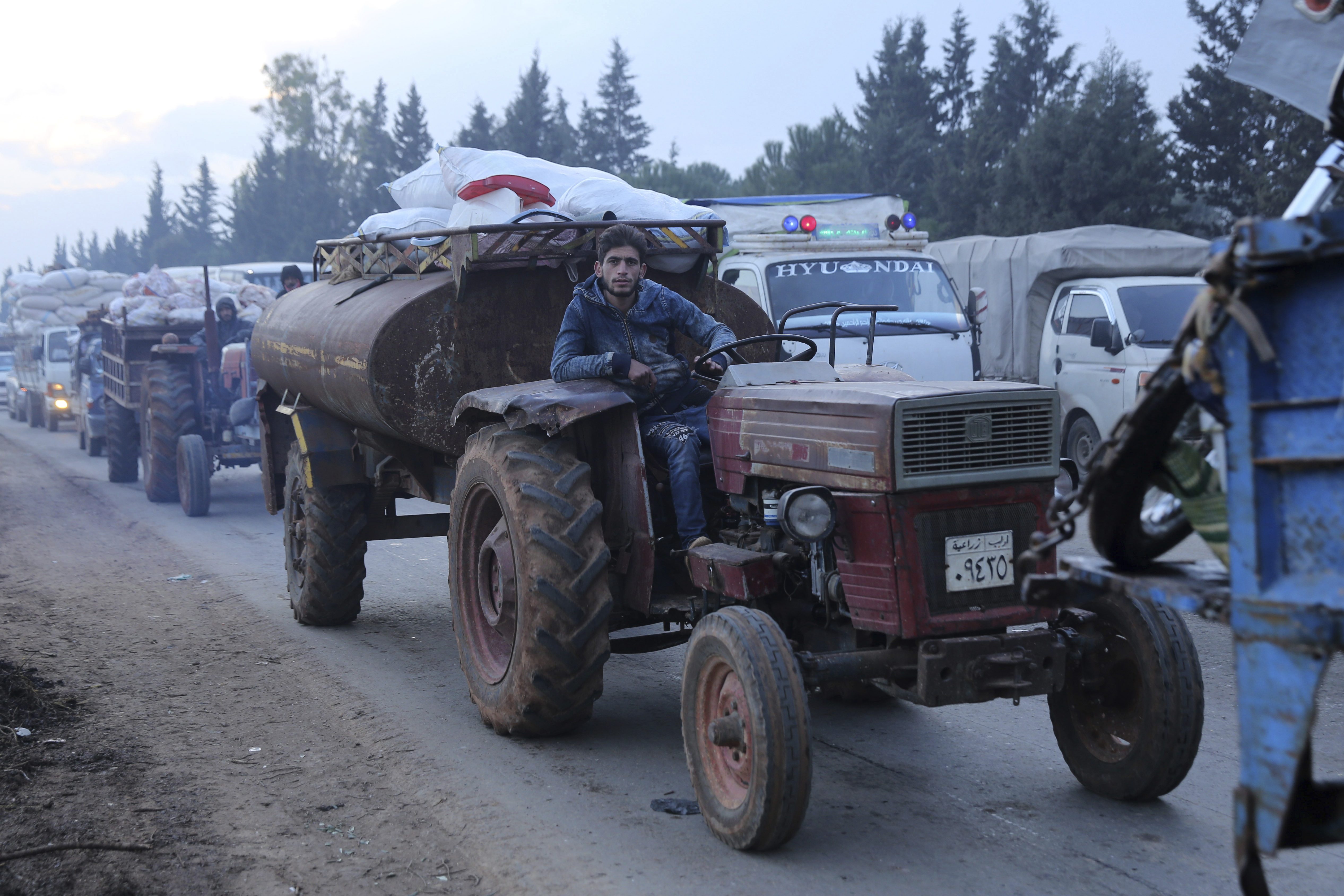 A man pulls a tanker trailer as civilians flee a Syrian military offensive in Idlib province on the main road near Hazano in Syria, on Tuesday.