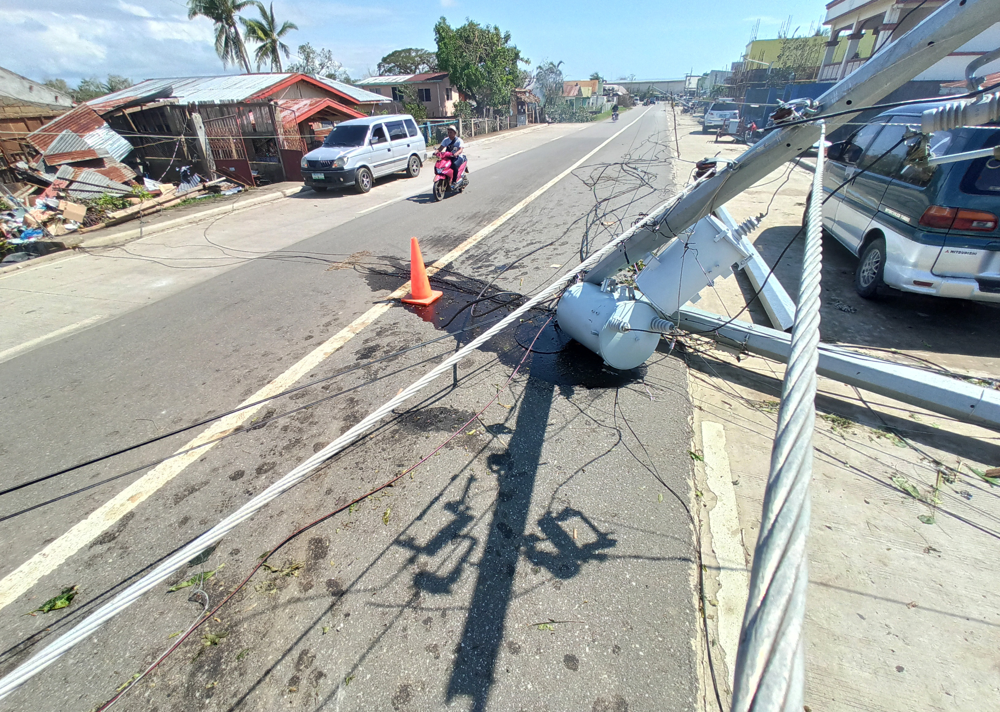 A man rides his motorcycle past an electrical post that was damaged by Typhoon Phanfone in Balasan Town, Iloilo province, central Philippines on Thursday.