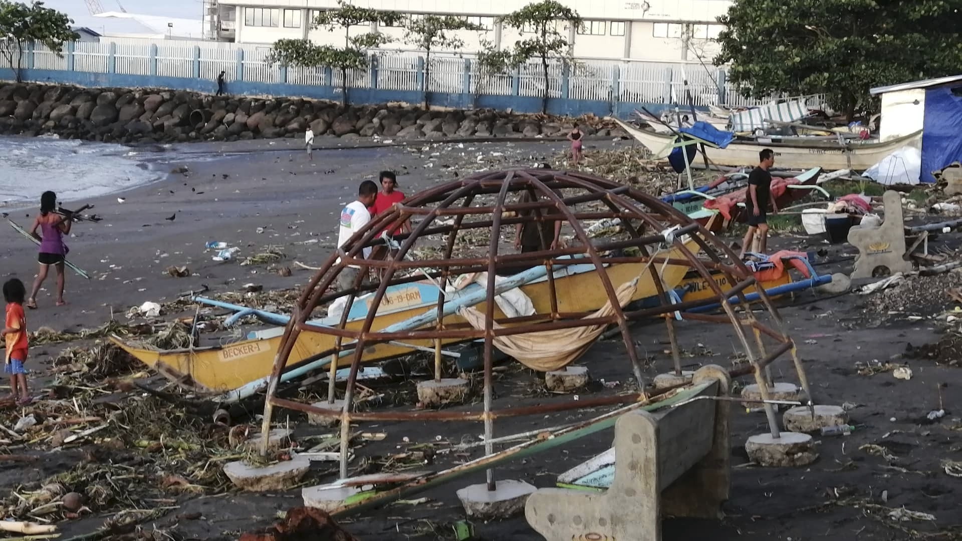 Residents walks beside an outrigger and playground equipment that were damaged by Typhoon Phanfone along a coastline in Ormoc city, central Philippines on Thursday.