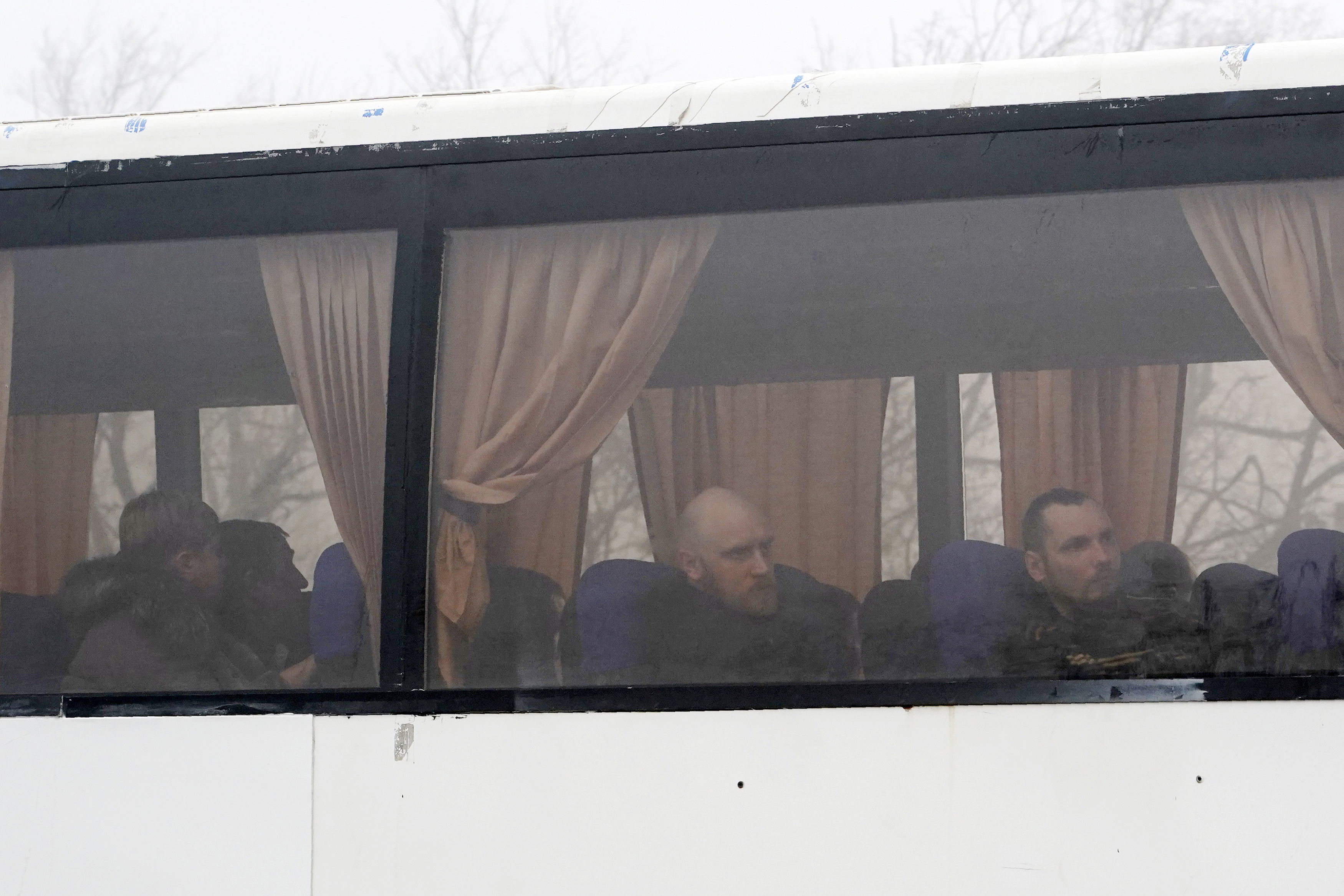 Russia-backed war prisoners are seen through a bus window, driving to be exchanged near Odradivka, eastern Ukraine, on Sunday.