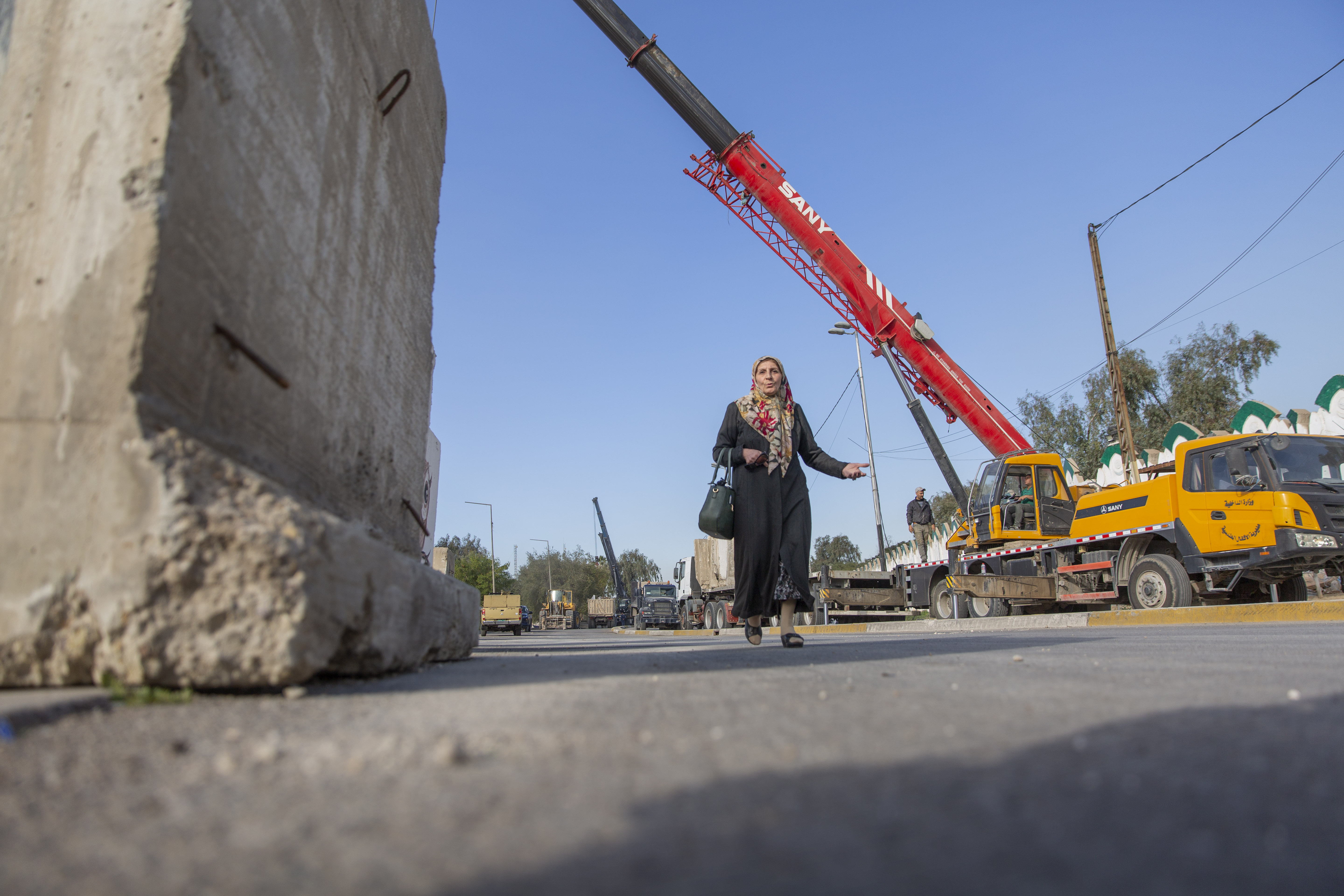 A woman passes by Iraqi security forces while they remove cement blocks and open the streets, that were closed for security concerns, around the Green Zone in Baghdad, Iraq, on Thursday.