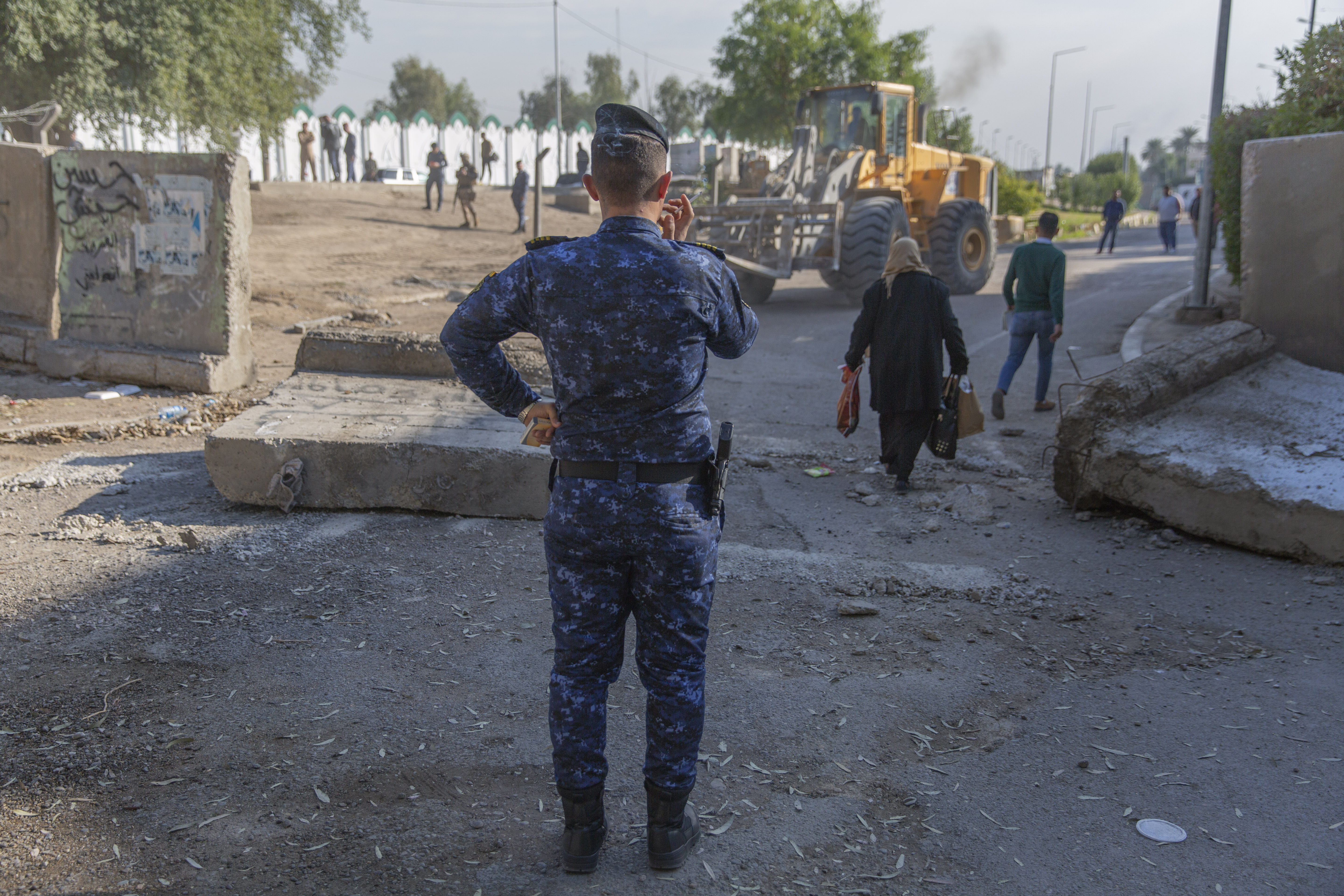 An Iraqi police officer instructs a bulldozer while Iraqi security forces remove cement blocks and opened the streets, that were closed for security concerns, around the Green Zone in Baghdad, Iraq, on Thursday.