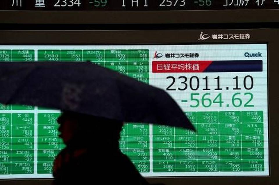 A pedestrian walks past a stock indicator displaying share prices of the Tokyo Stock Exchange in Tokyo on January 8, 2020.