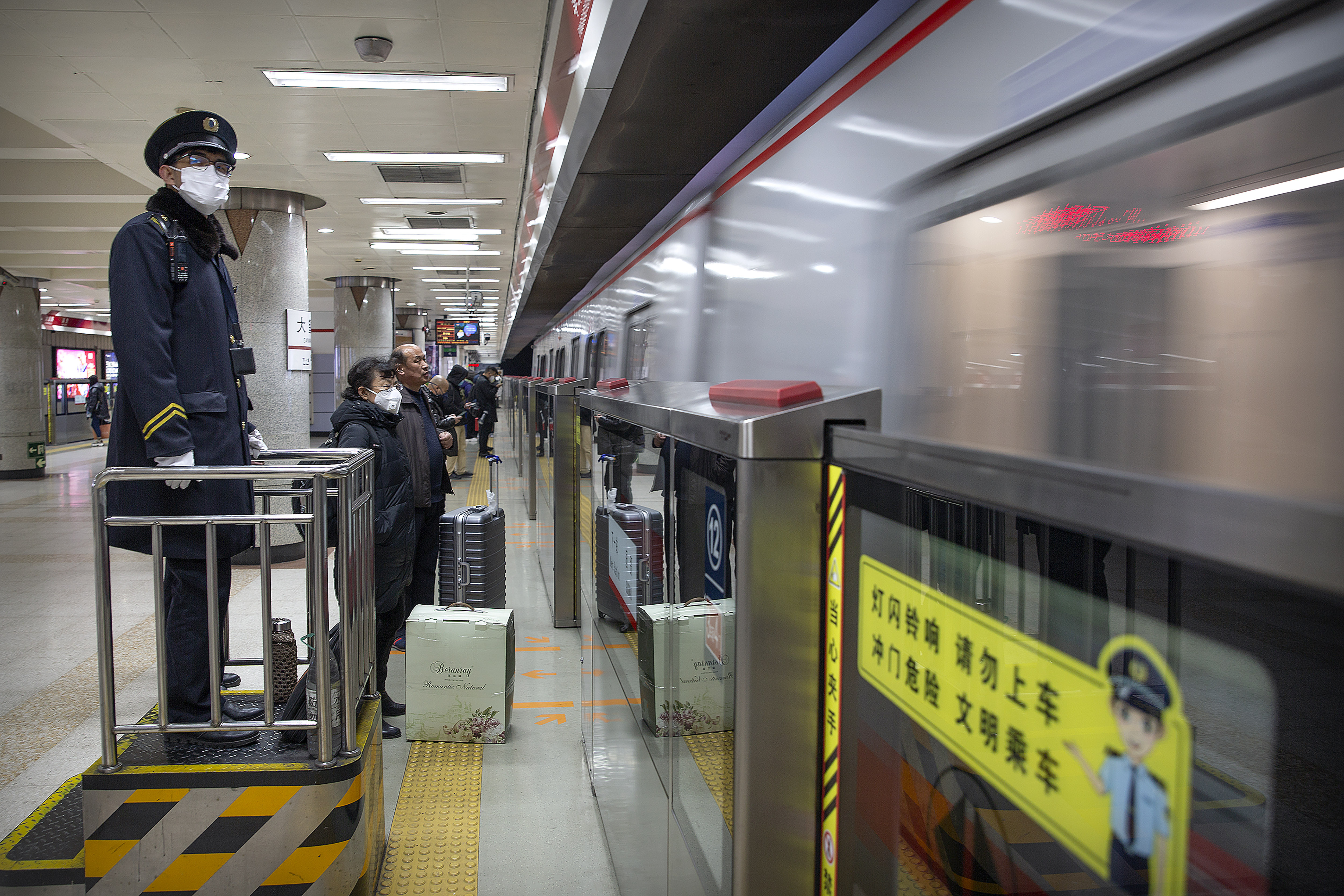 A conductor wears a face mask as a train arrives at a subway station in Beijing