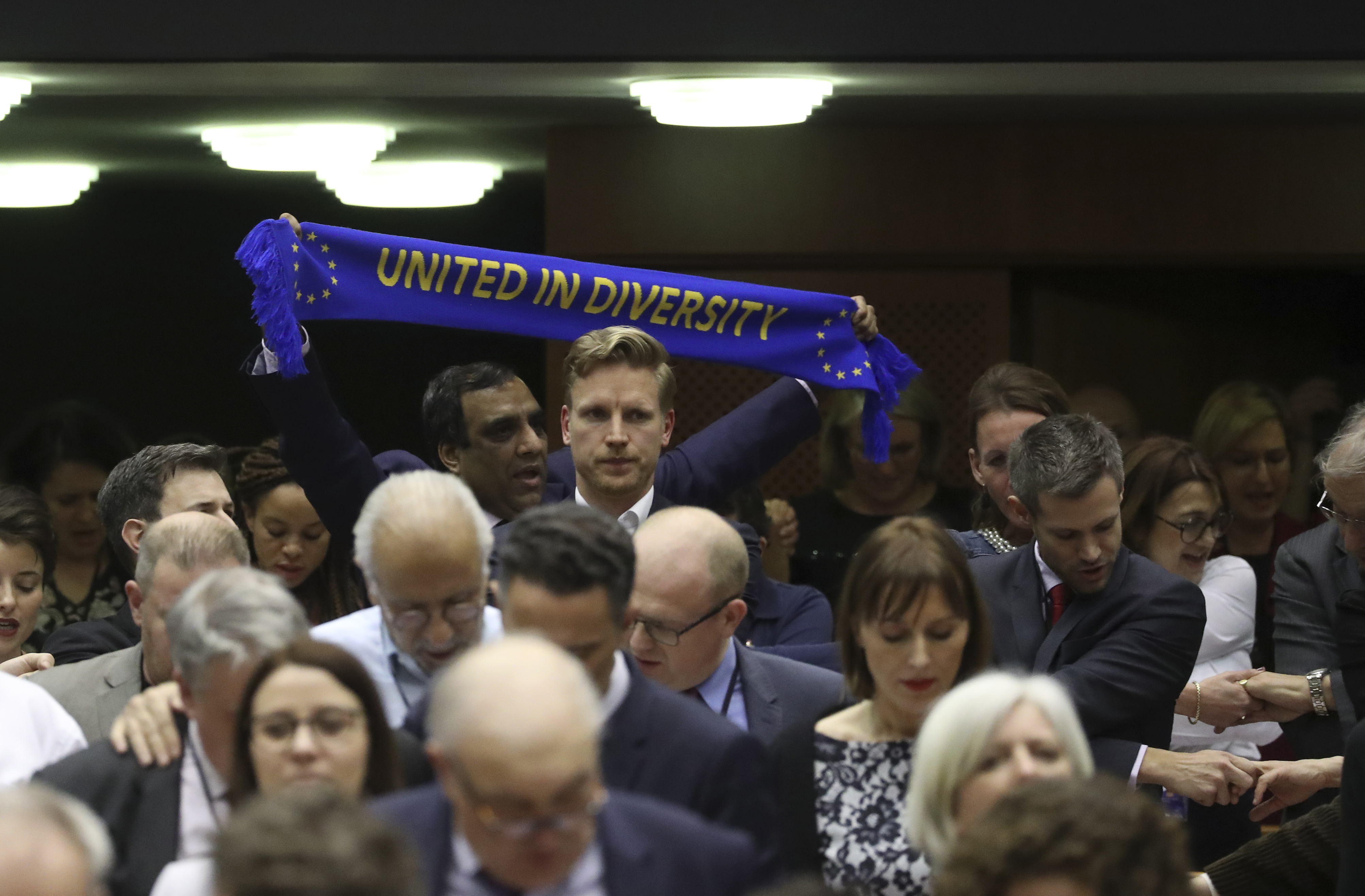 MEP's hold hands and banners after a vote on the UK's withdrawal from the EU, the final legislative step in the Brexit proceedings, during the plenary session at the European Parliament in Brussels