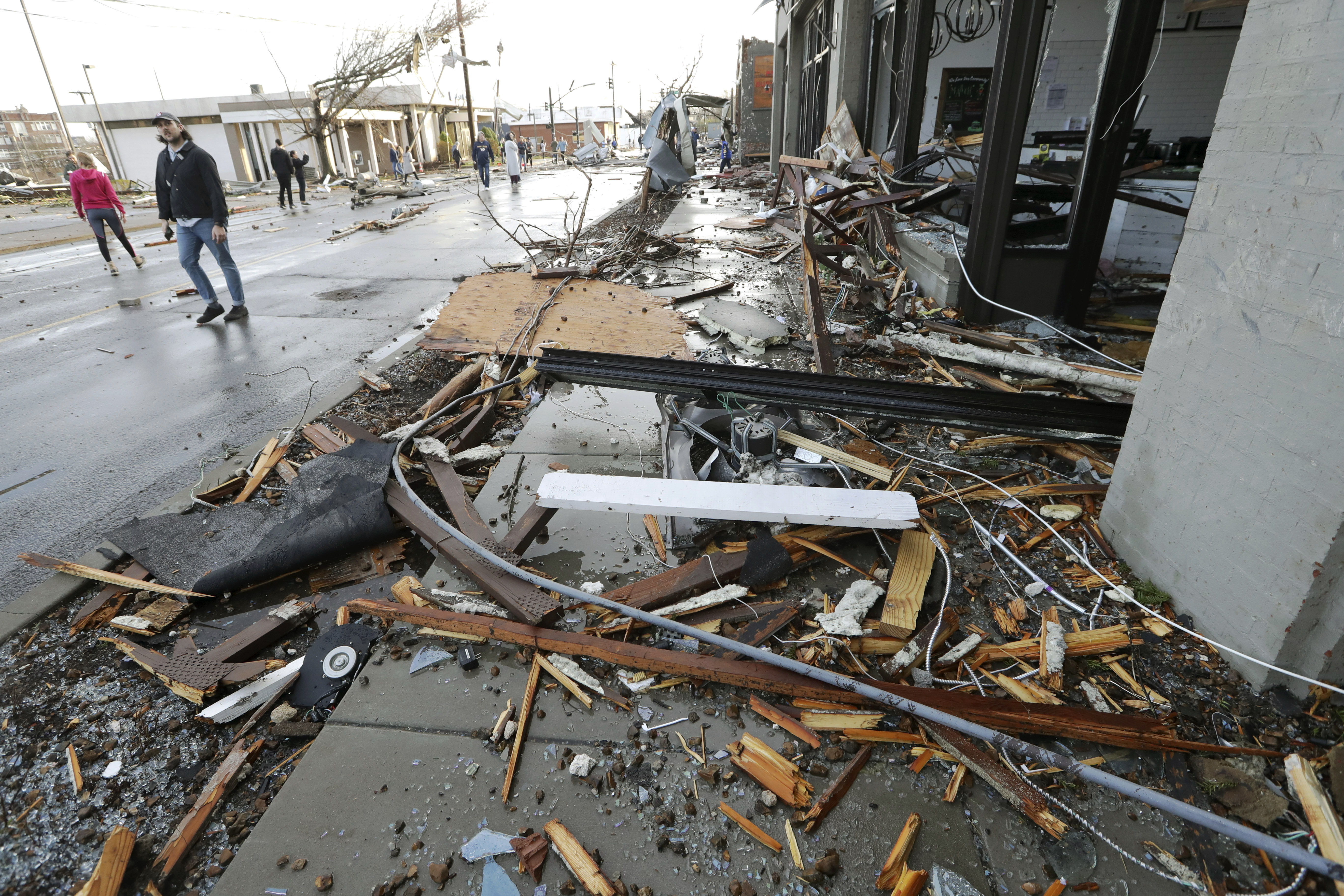 People pass by businesses destroyed by storms Tuesday, in Nashville, Tenn.