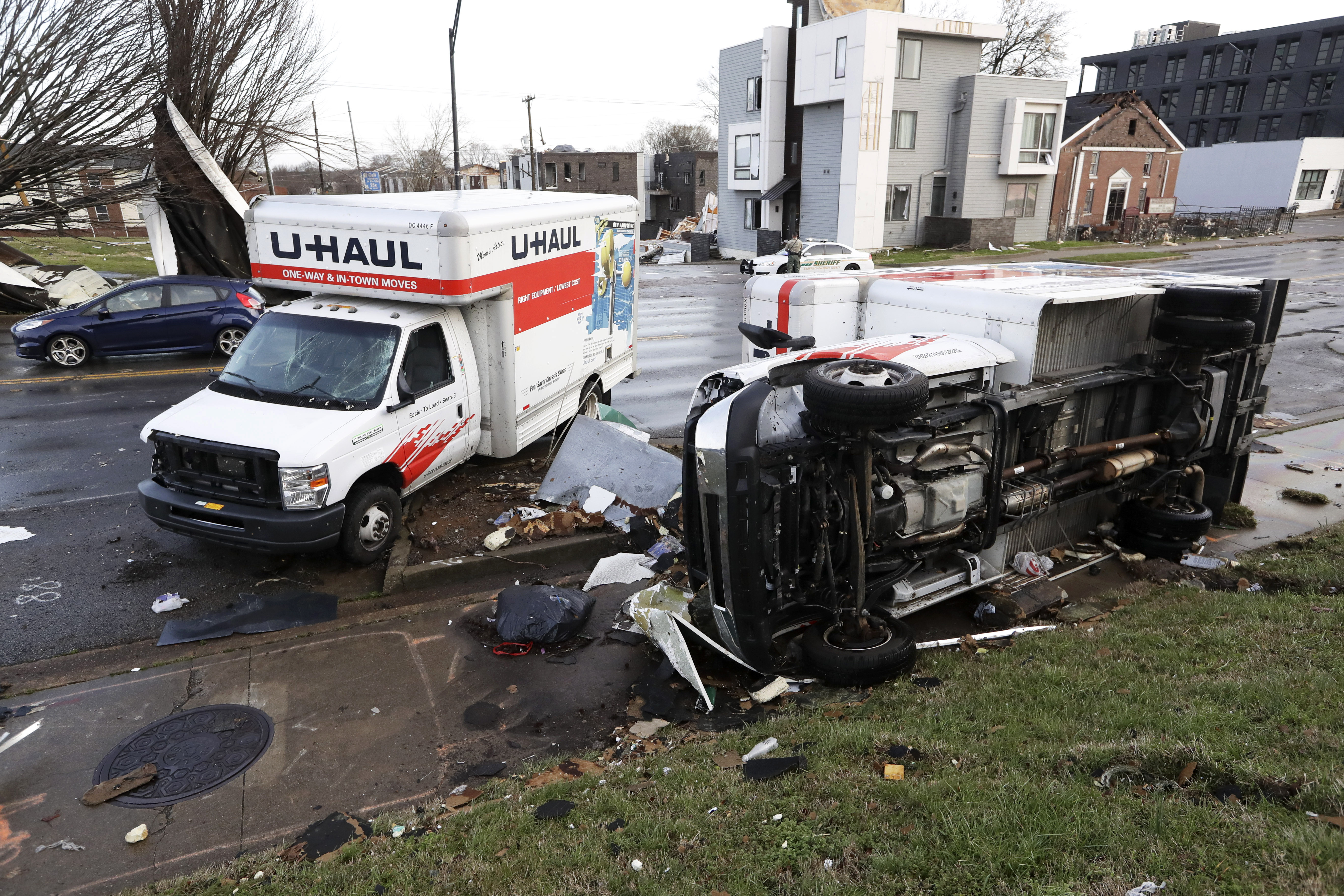 Damaged trucks sit on a sidewalk as well as the street following a deadly tornado, Tuesday.