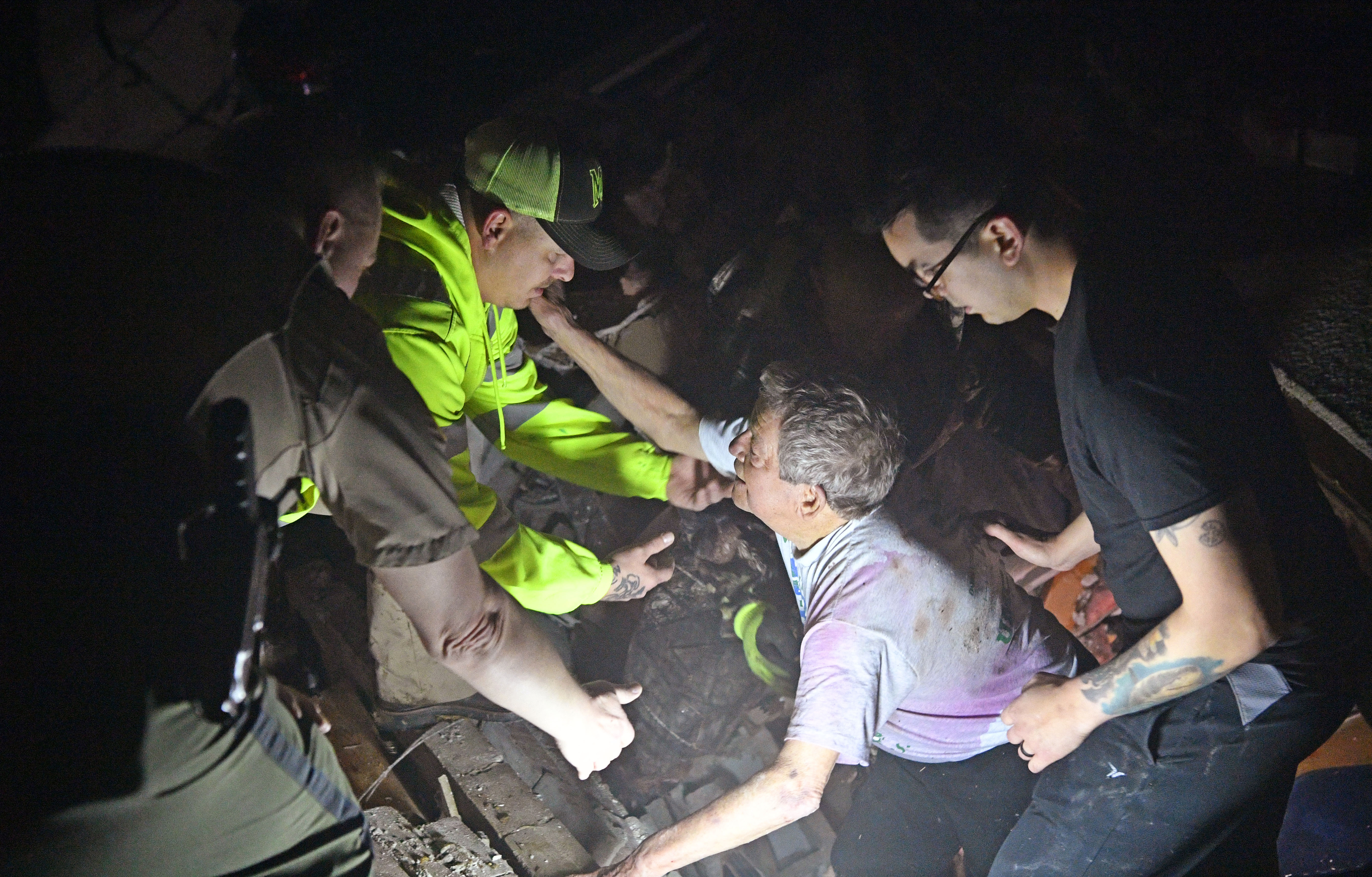 Bill Wallace reaches out to rescue workers who freed him from his home that collapsed on him and his wife Shirley trapping them under rubble after a tornado hit Mt. Juliet, Tenn., on Tuesday.