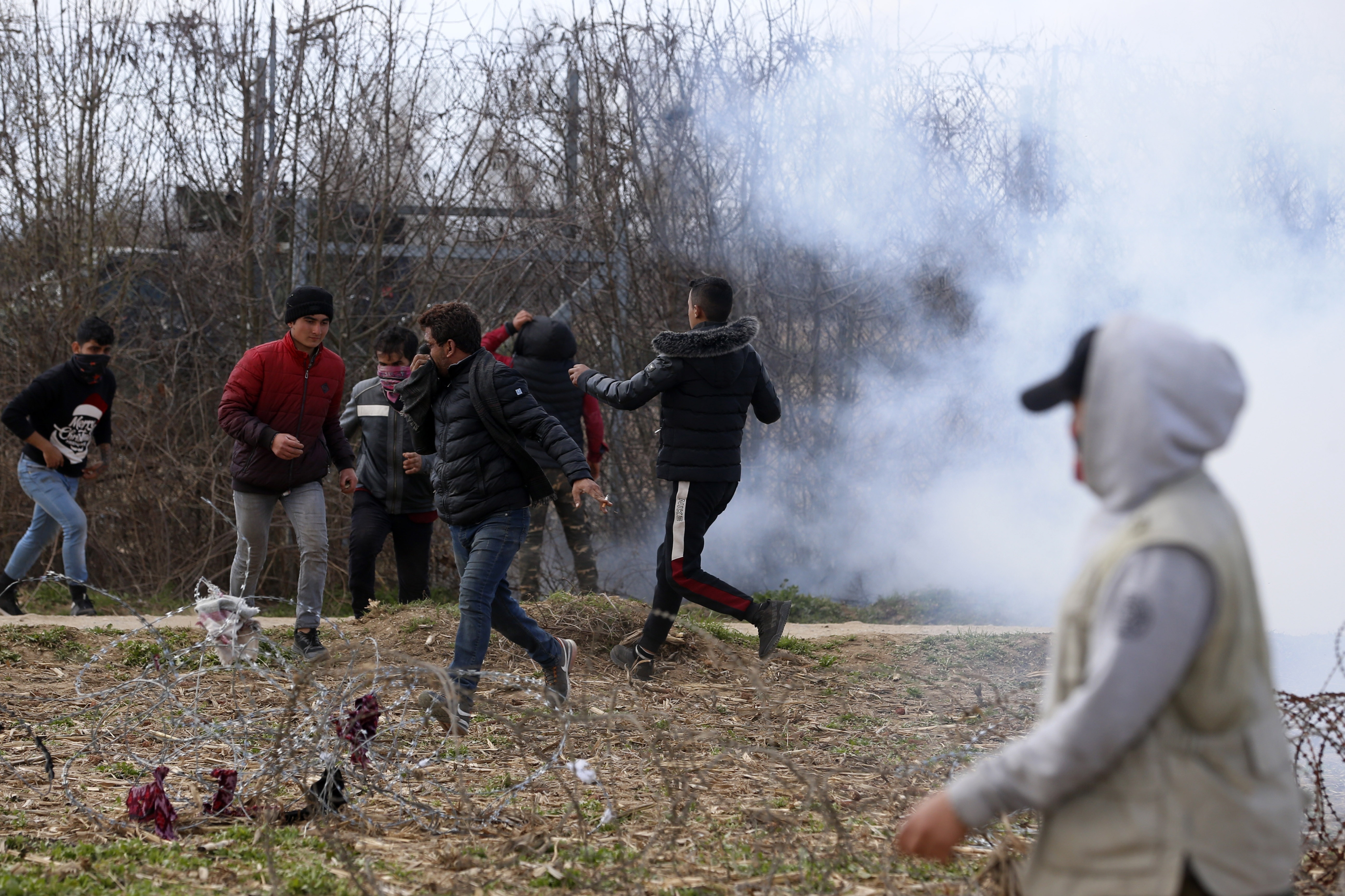 Greek firefighters spray water as migrants stand near a border fence on the Turkish side during clashes with the Greek riot police at the Turkish-Greek border in Pazarkule, Edirne region, on Saturday.