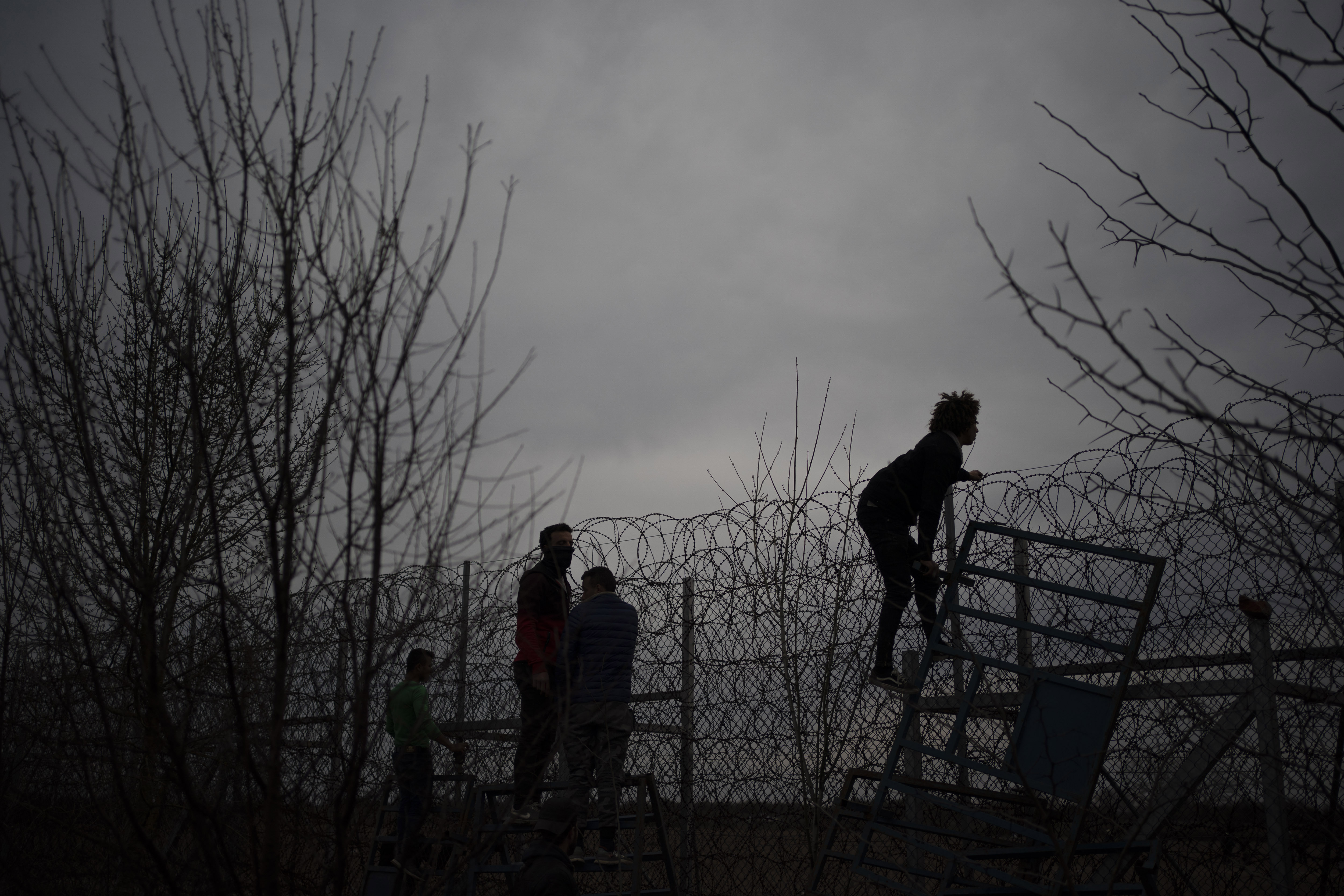 A migrant climbs a fence during clashes with the Greek riot police at the Turkish-Greek border in Pazarkule, Edirne region, Turkey, Friday.