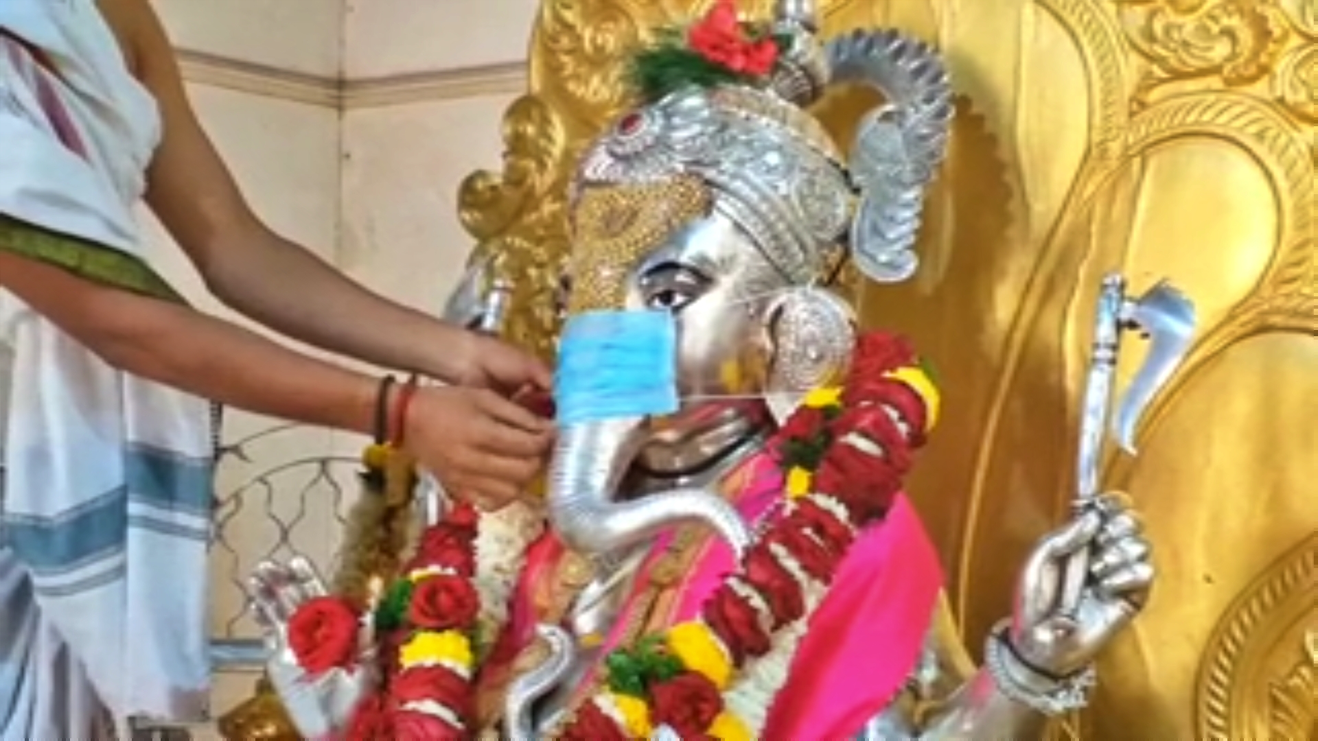 Priest puts face mask on Ganesha at Siddhivinayak temple