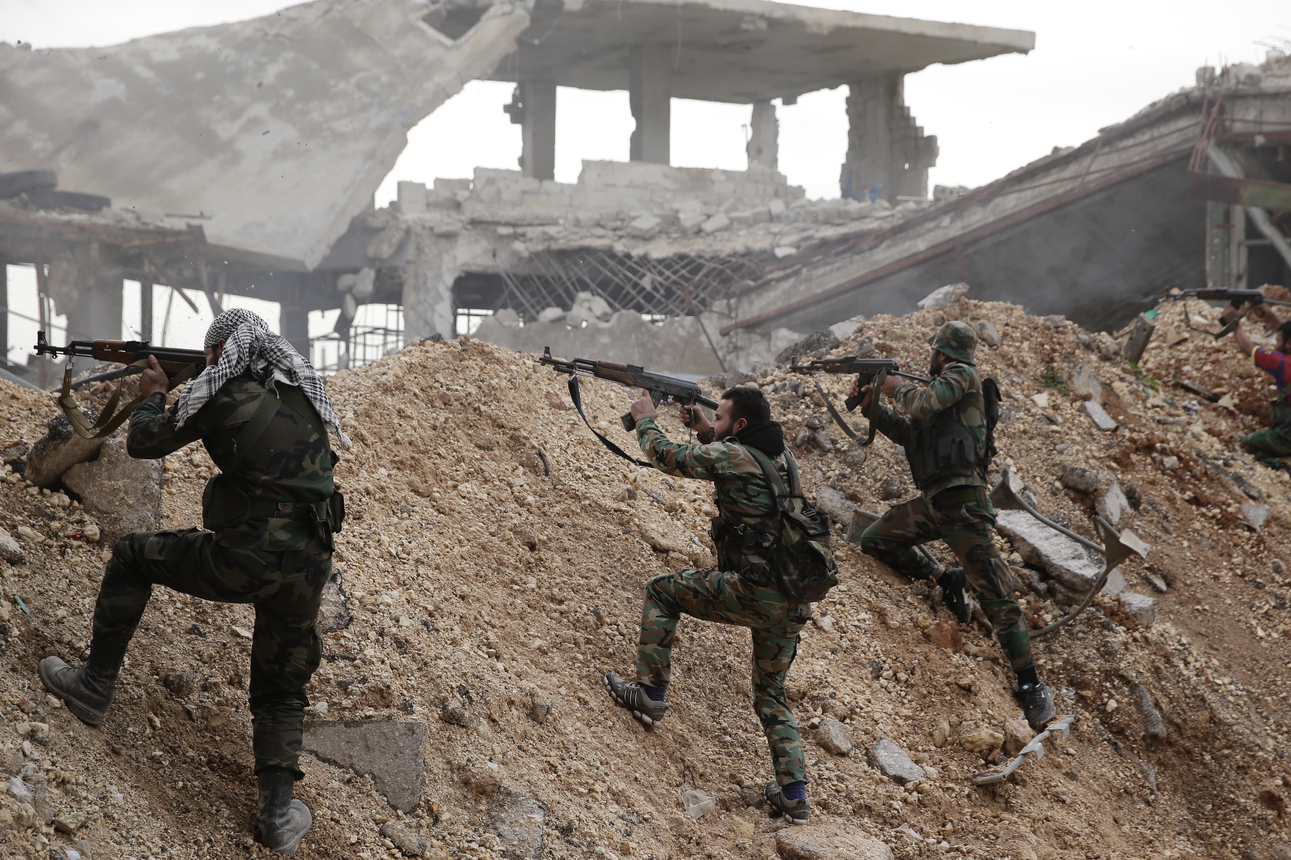 Syrian army soldiers fire their weapons during a battle with rebel fighters at the Ramouseh front line, east of Aleppo, Syria.