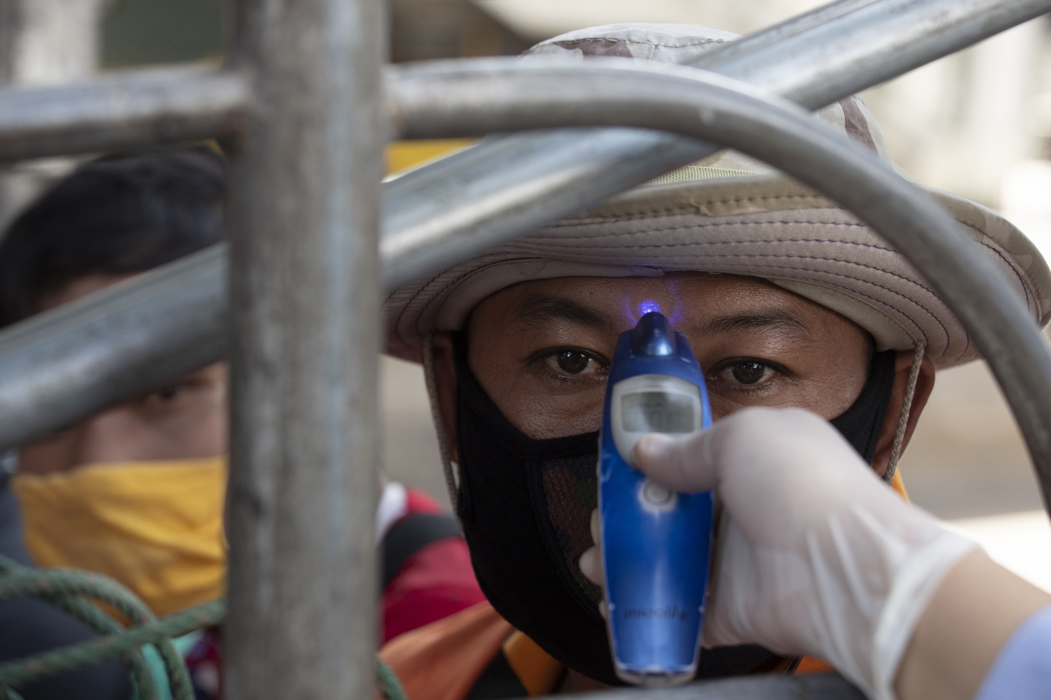 A health officer checks the temperature of a passenger in truck at a health check point in Bangkok, Thailand