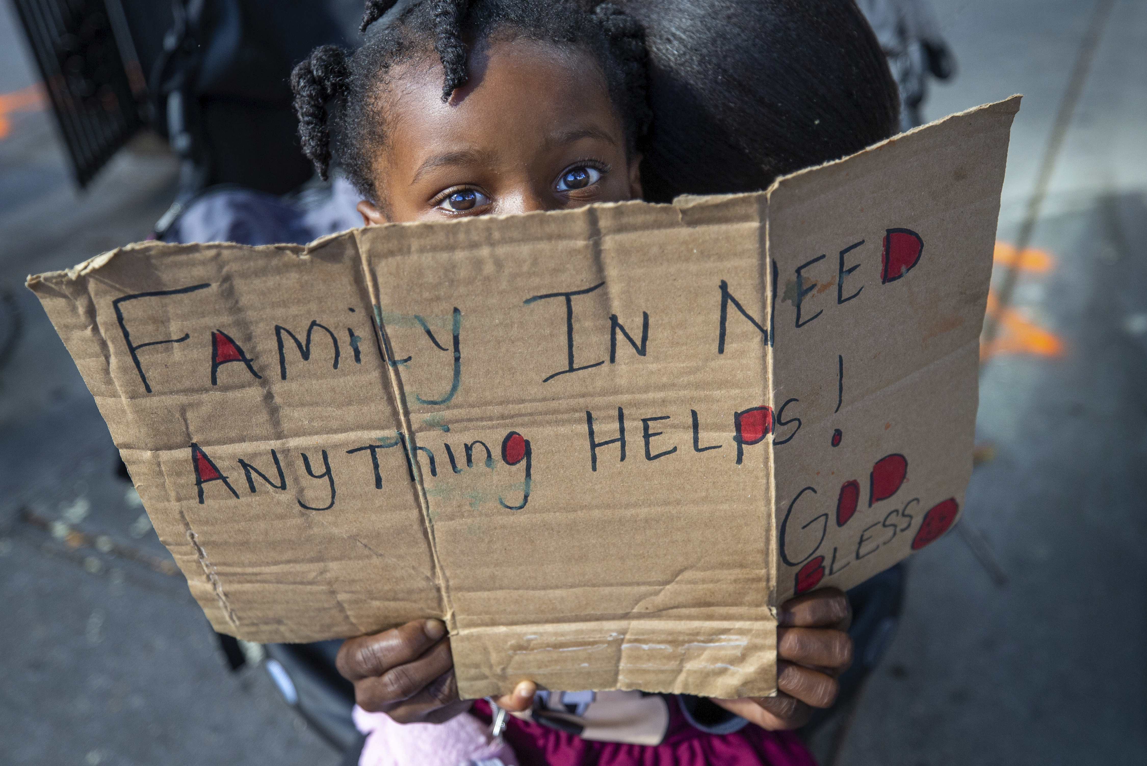 Nyla Clark, 3, accompanied by her mother, Chavonne Clark, sits in a baby stroller at a corner in New Orleans, hoping to get a few dollars from an occasional passerby