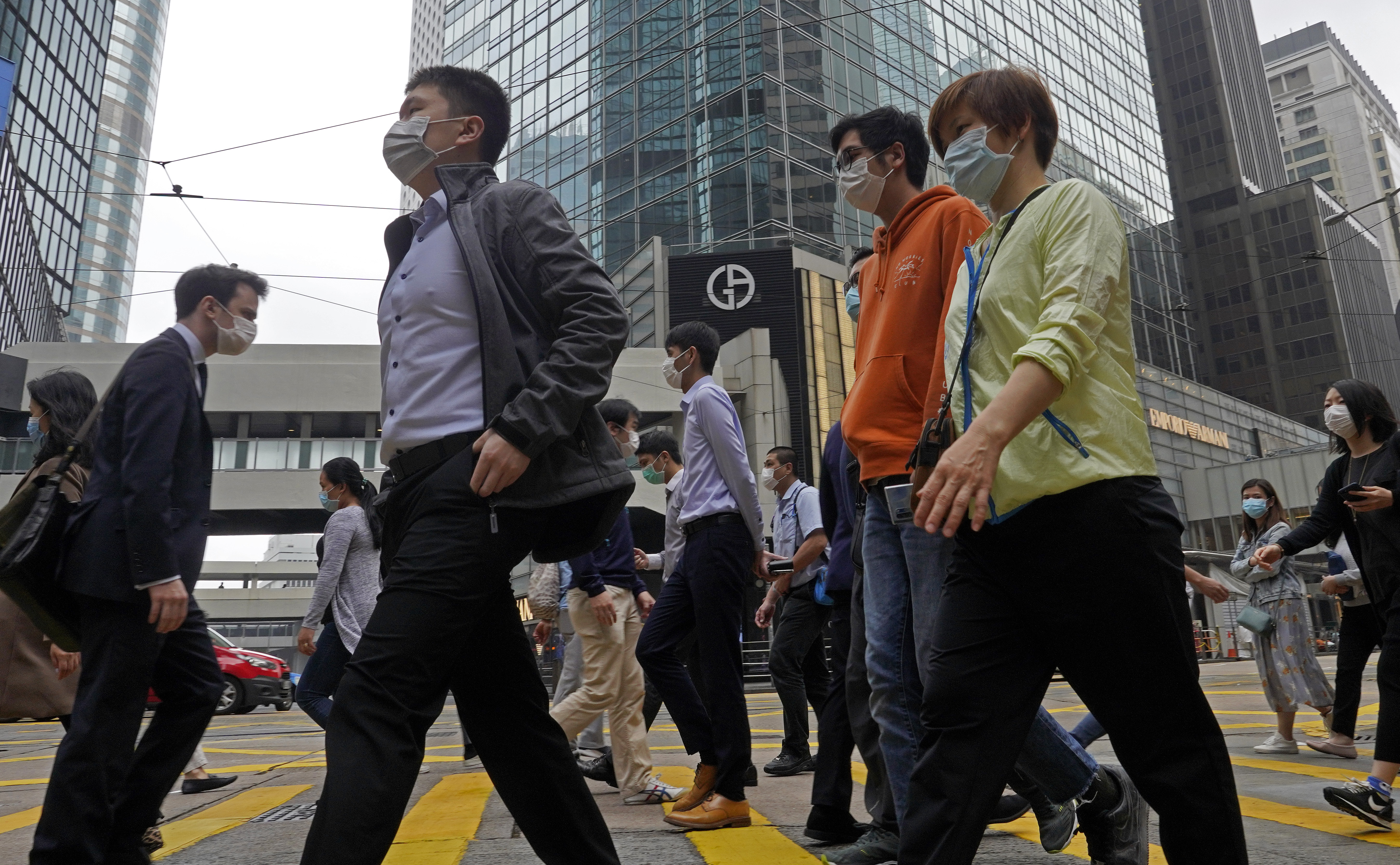 People wearing face masks walk at a downtown street in Hong Kong Thursday