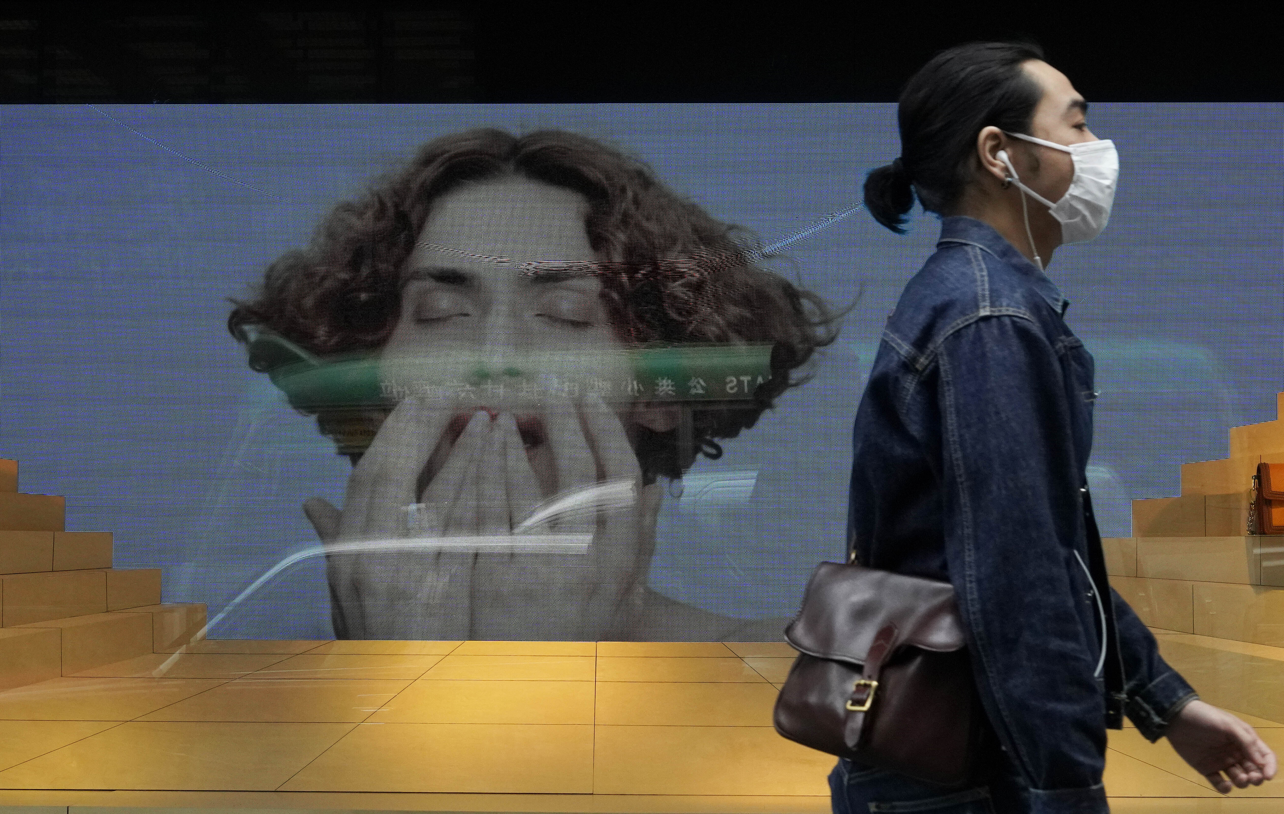 A man wearing face mask walks past a fashion shop at a downtown street in Hong Kong