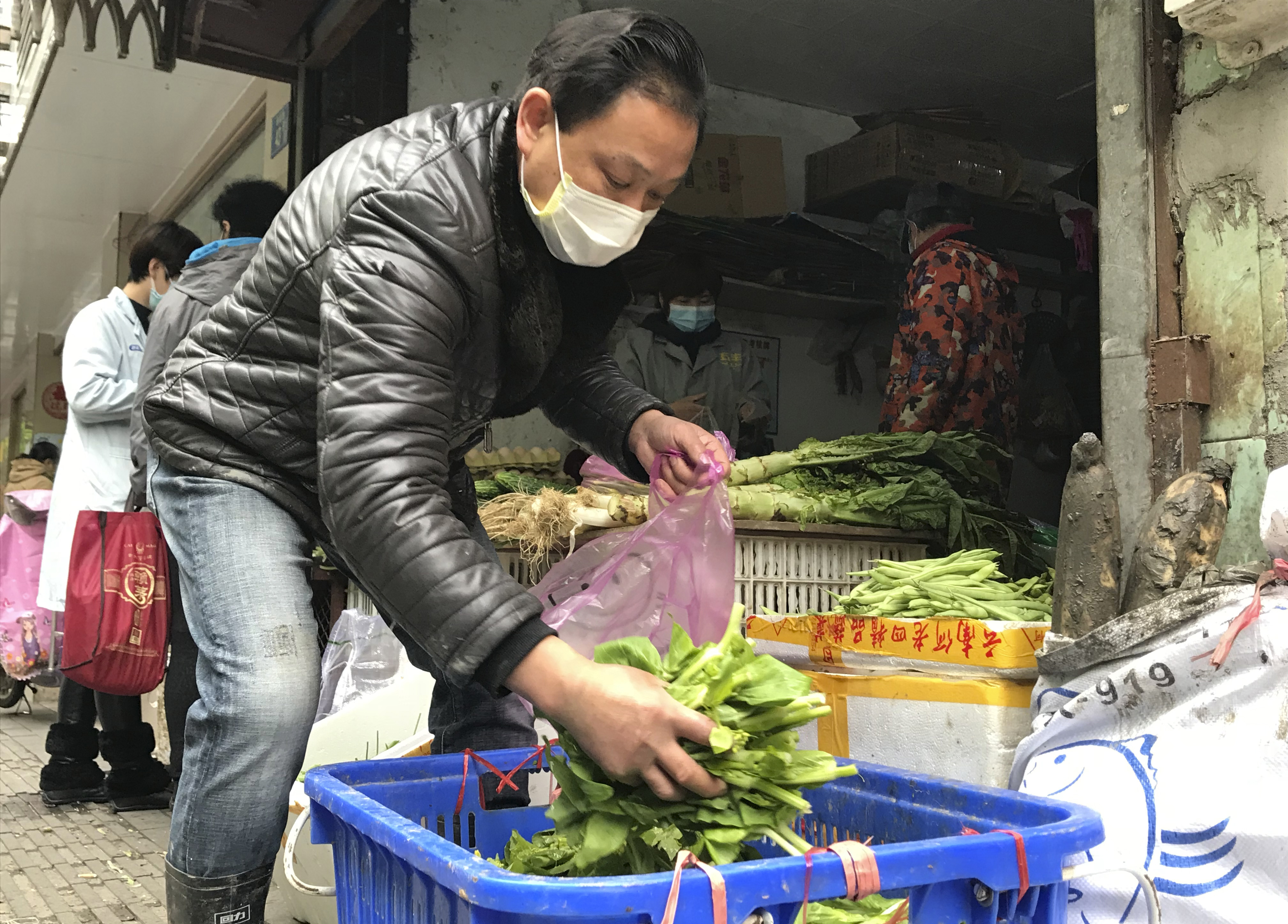 A vegetable vendor grabs some produce at a store in Wuhan in central China's Hubei province
